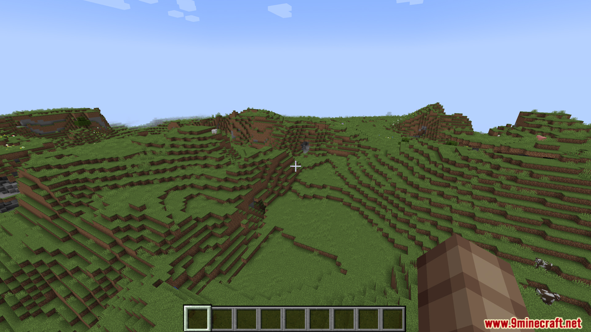 Player looking at a grassy landscape with hills and cows