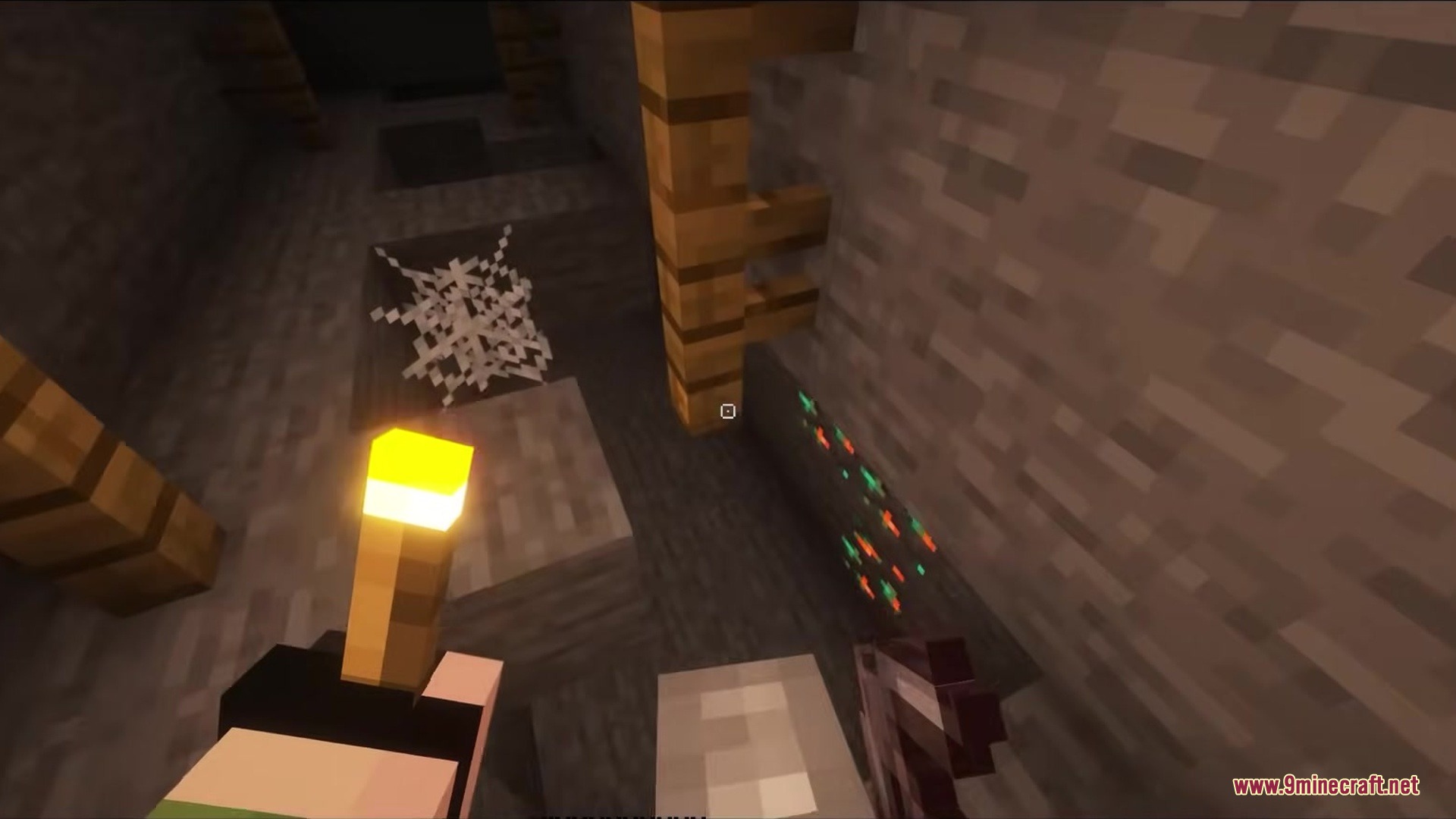 Player holding a torch in a dark mineshaft with a square crosshair