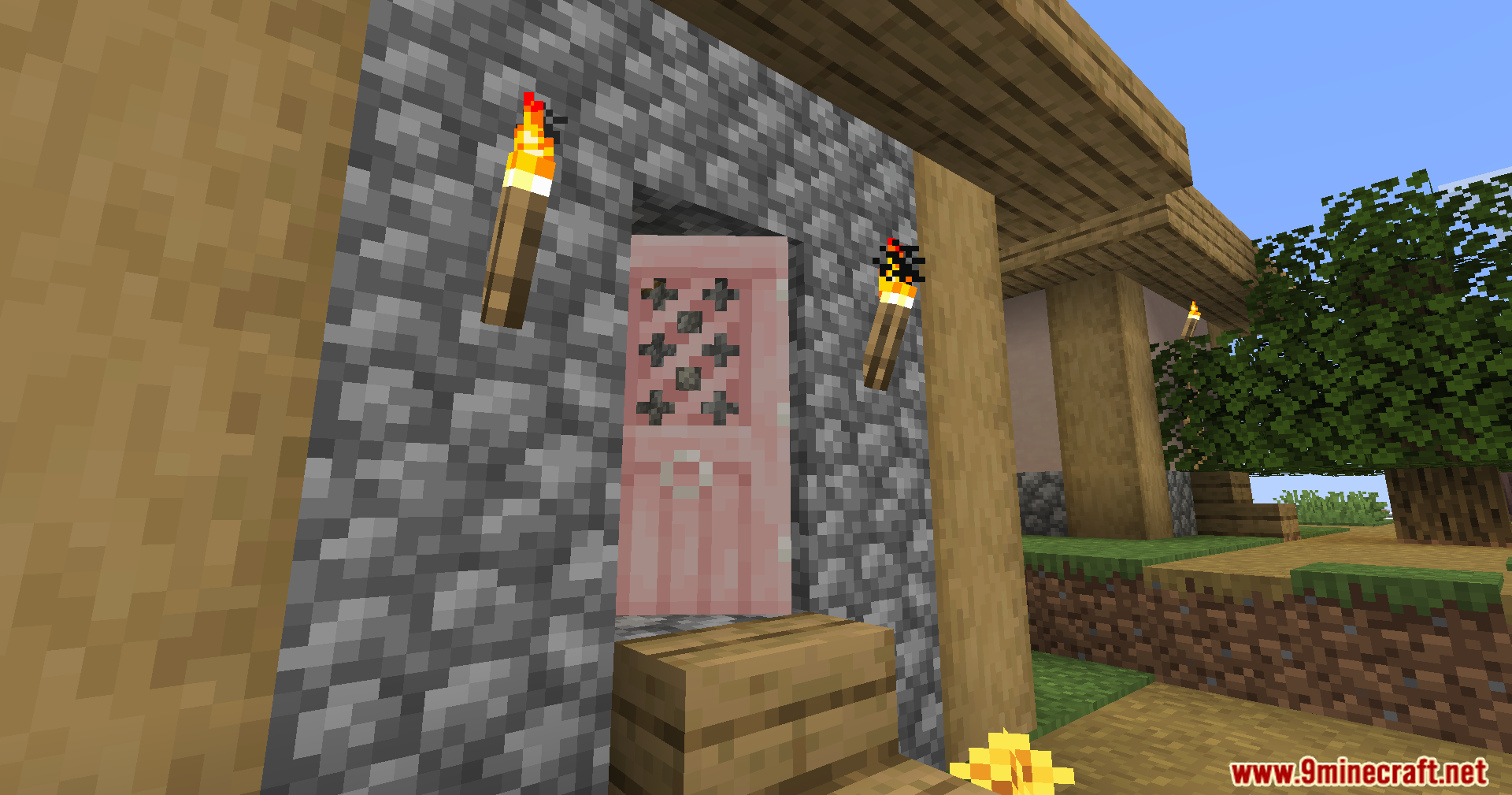 A closed pink cherry wood door set into a cobblestone house wall