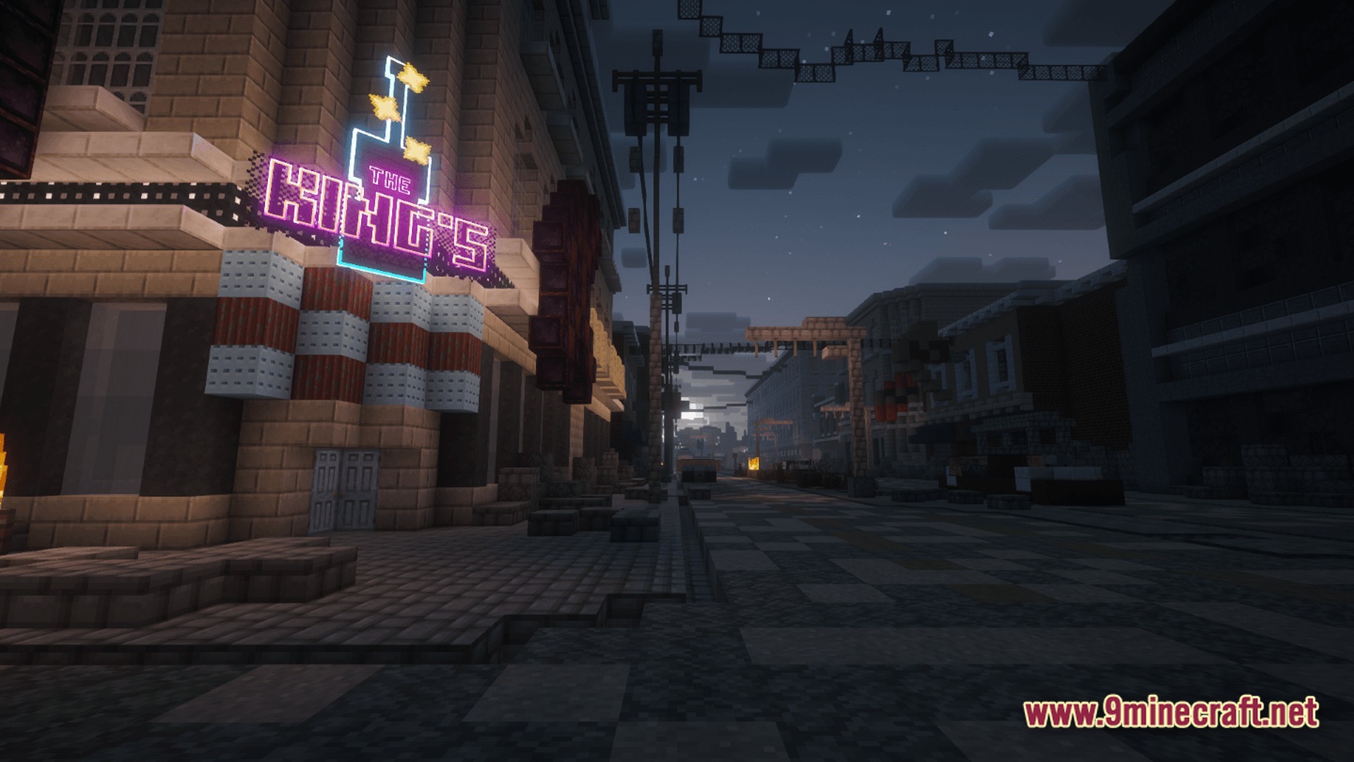 A neon sign for the king's hangs over a dark, abandoned city street at night