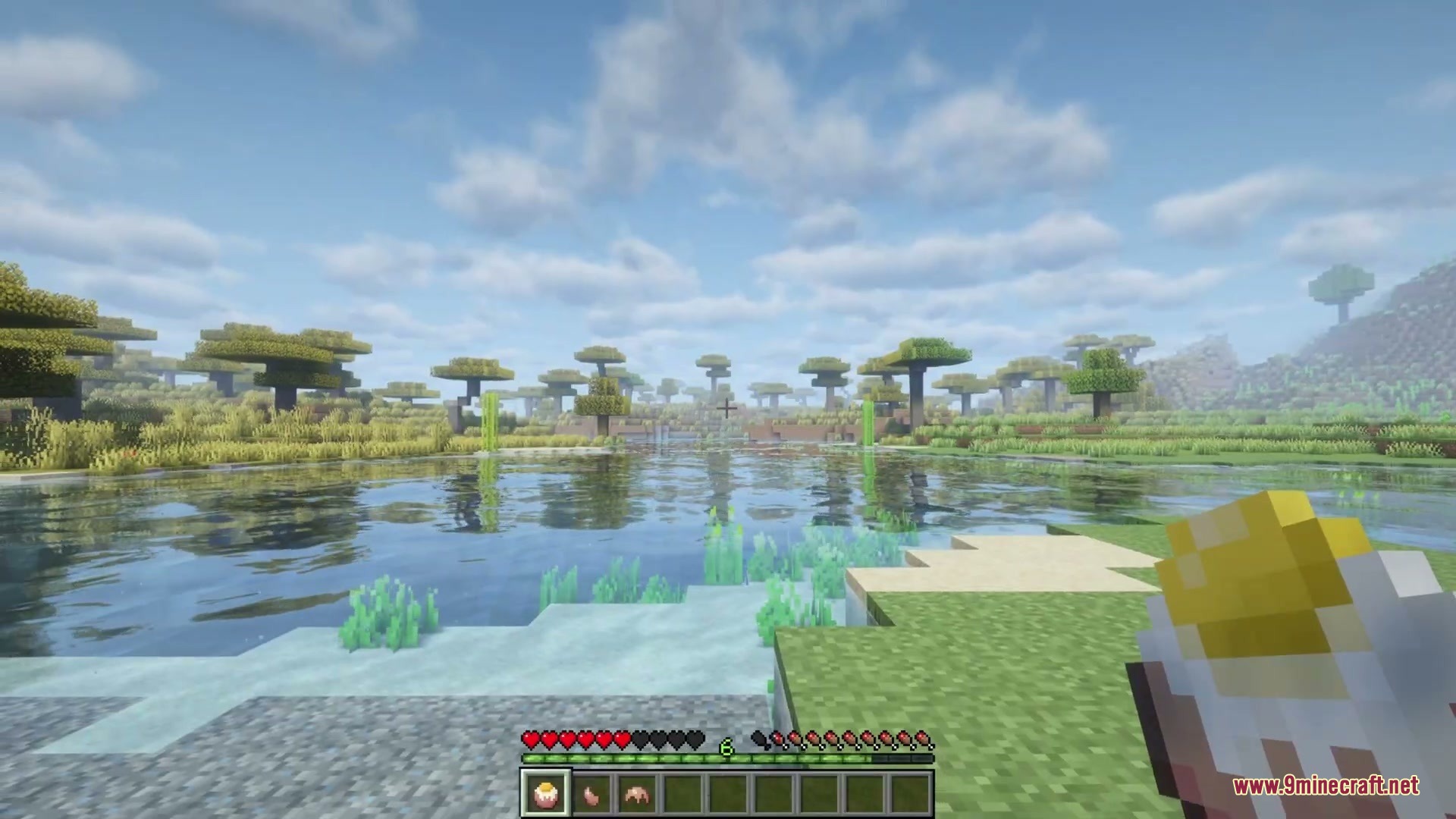 Anachronistic Wilds Mod (1.20.1) – Summon And Breed Extinct Prehistoric Wildlife 9 Player holding a food item while looking at a scenic prehistoric lake landscape