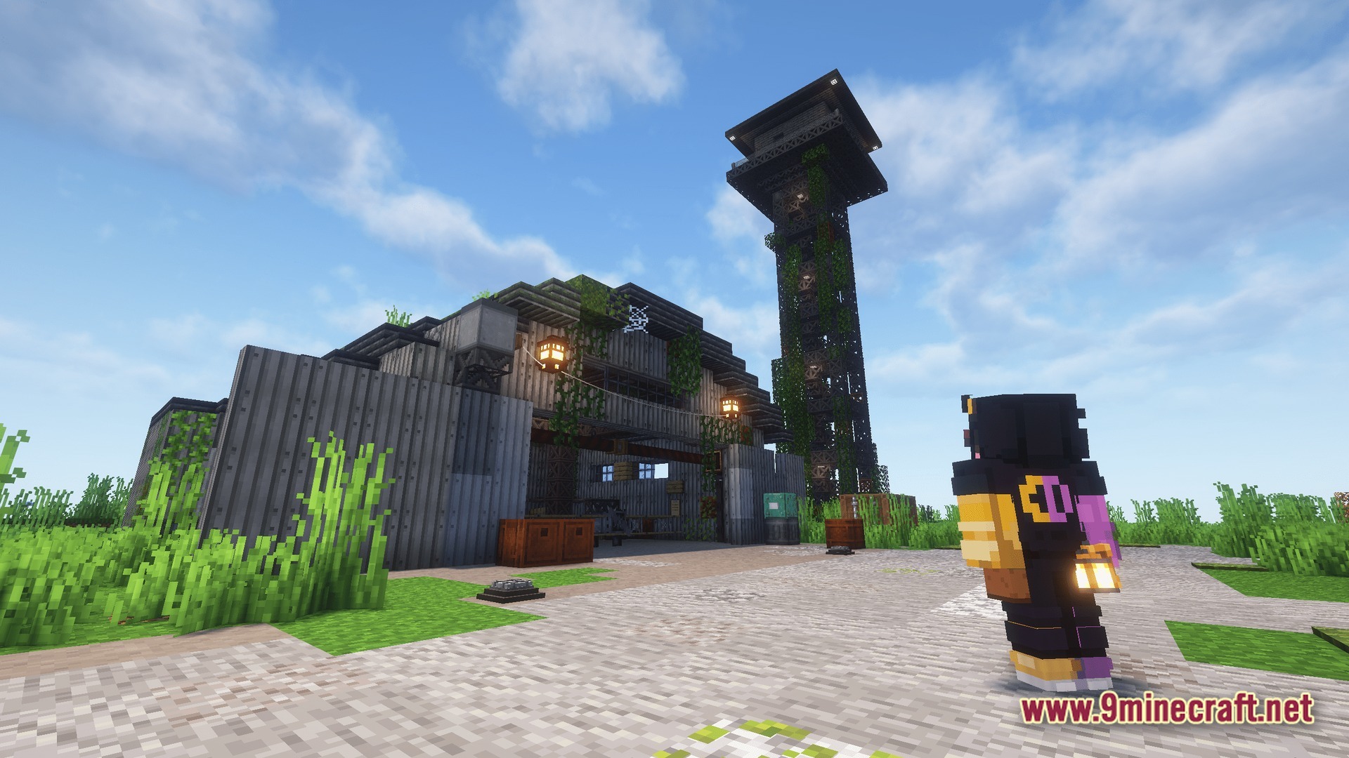 An industrial warehouse and a tall observation tower stand in a grassy biome under a clear sky
