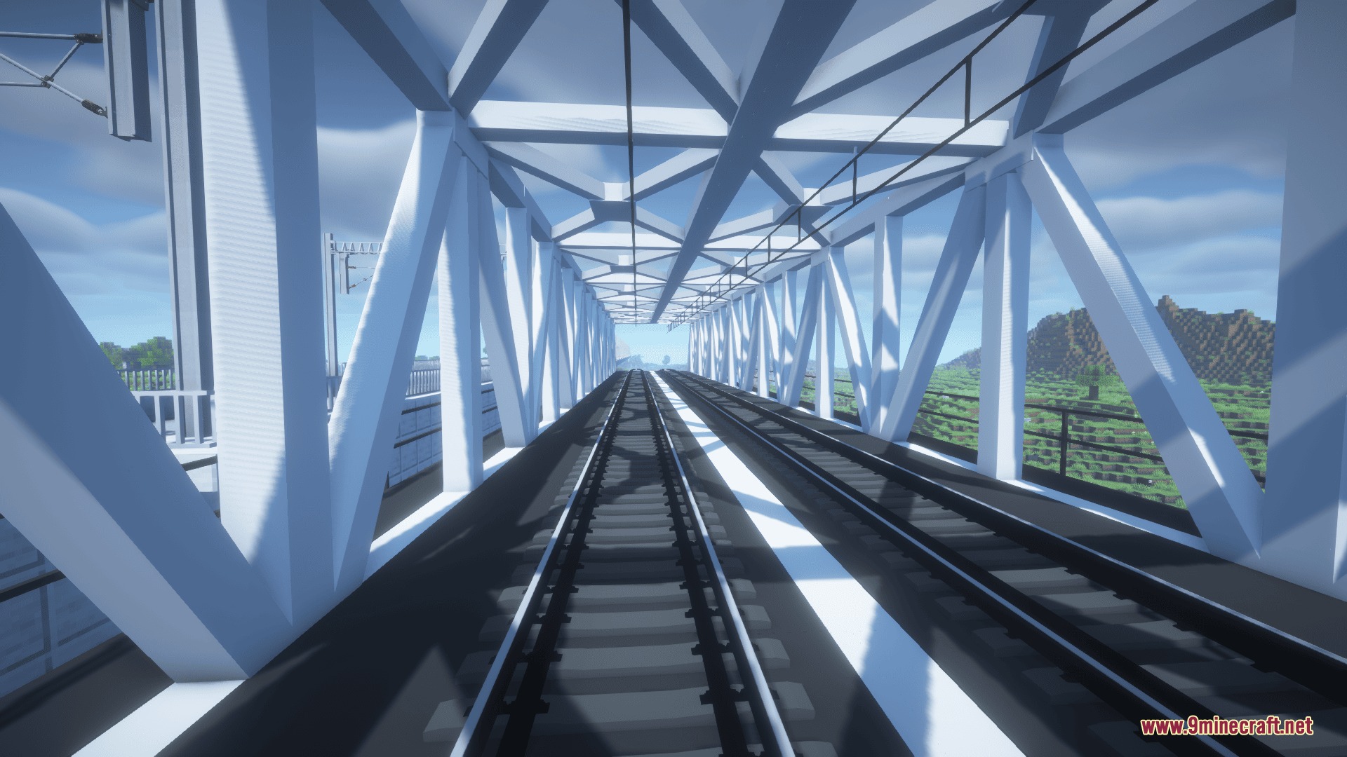 View of two railway tracks inside a white metal truss bridge structure