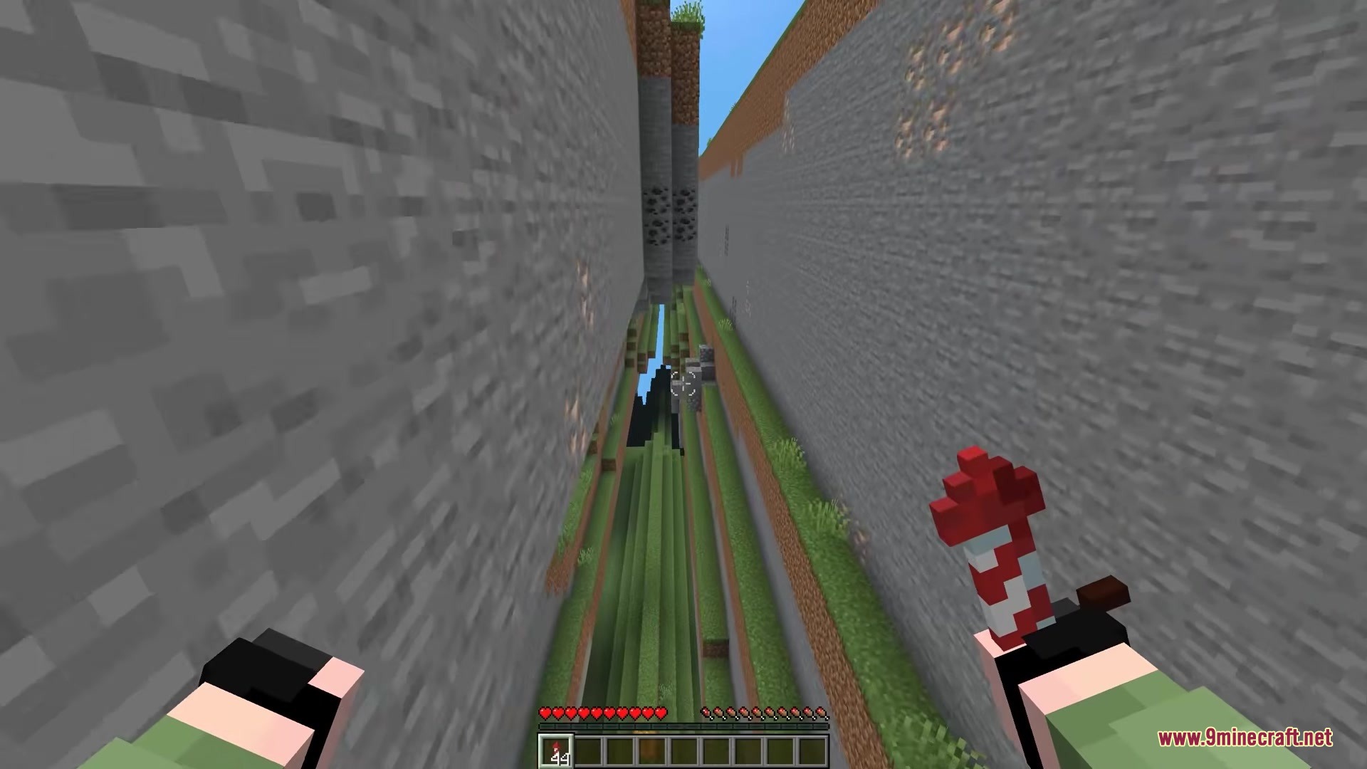 Player holding a firework rocket while flying through a deep vertical terrain gap