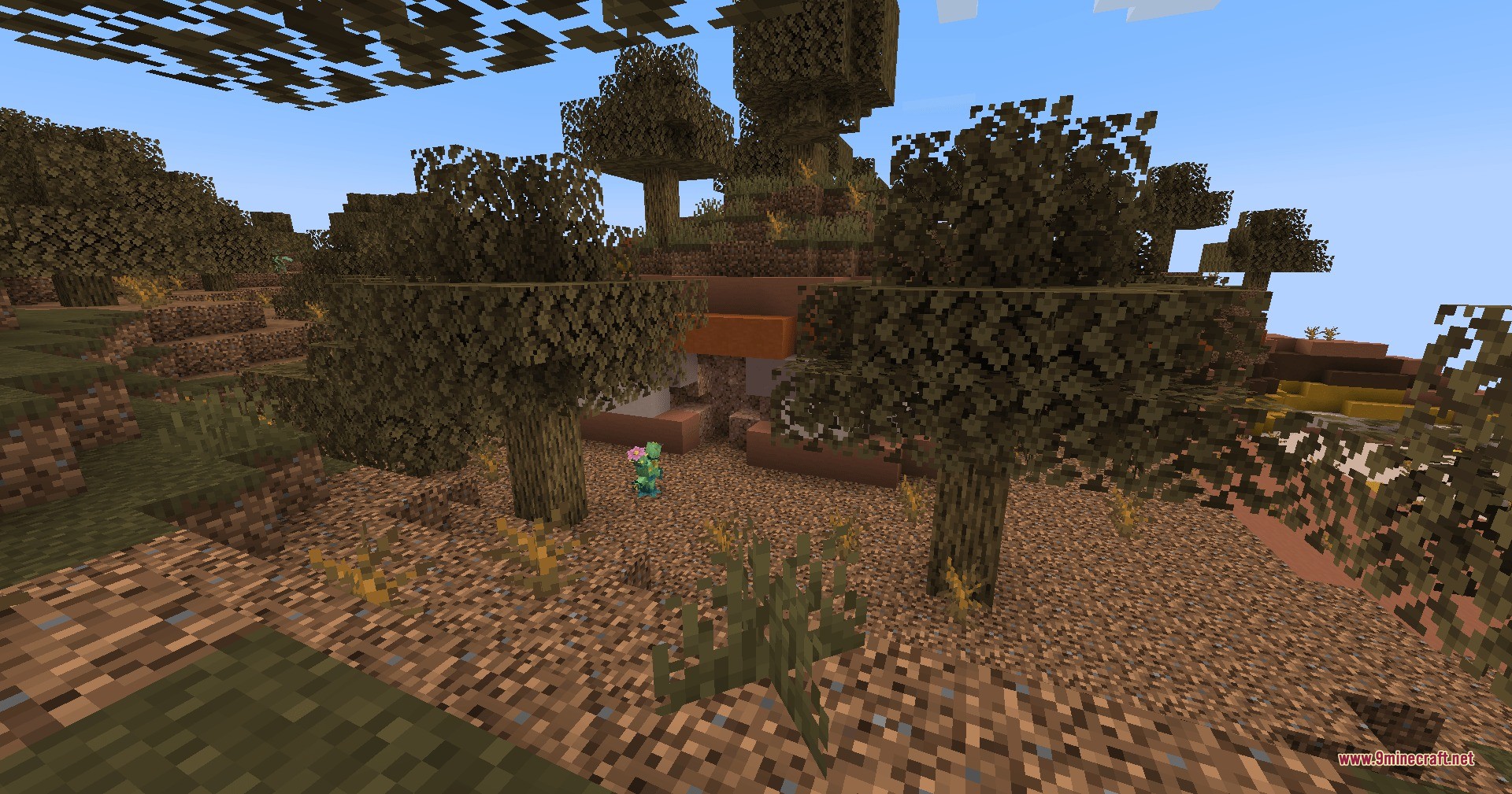 A small green creature stands outside a mysterious mound in the badlands
