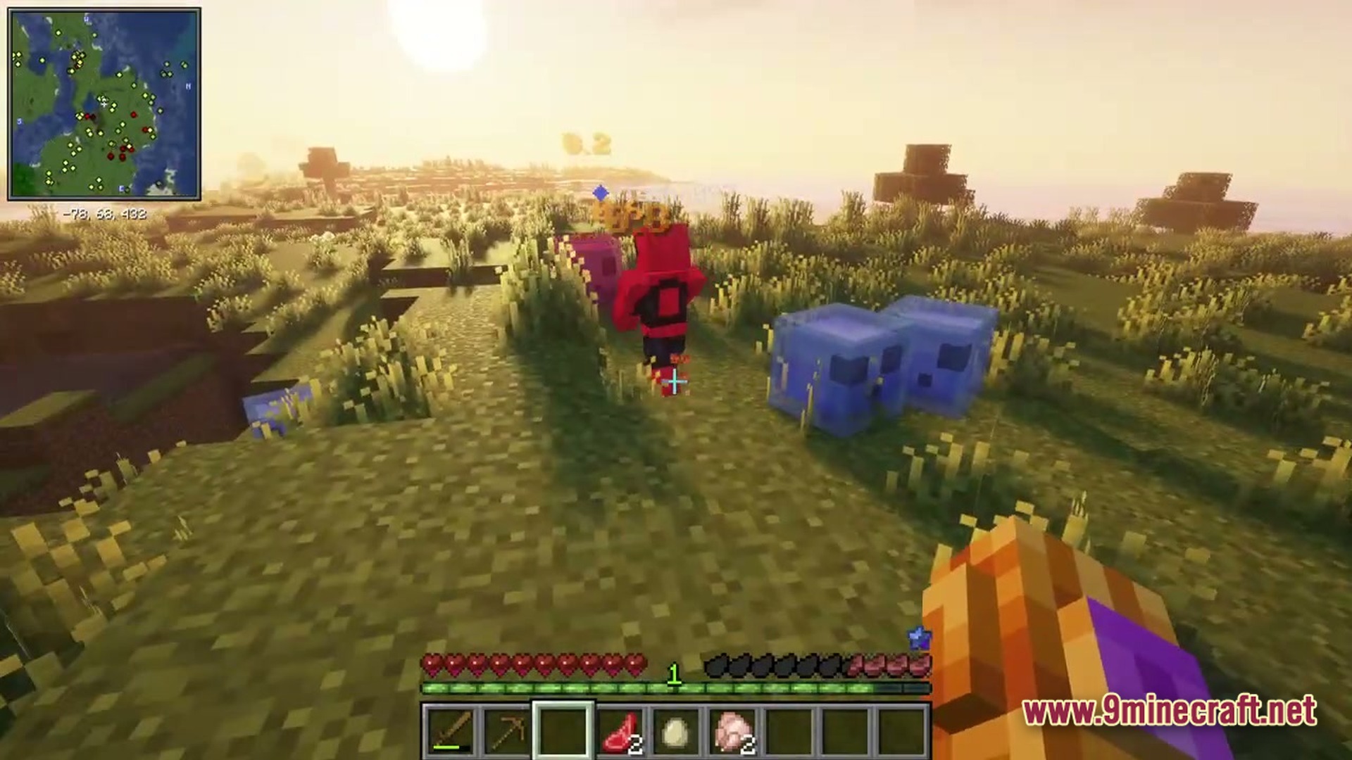 A player fights blue and pink slimes in a grassy field during a sunset