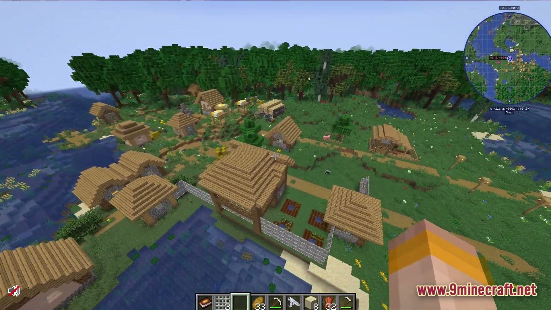 An aerial view of a minecraft village situated between a forest and a river biome