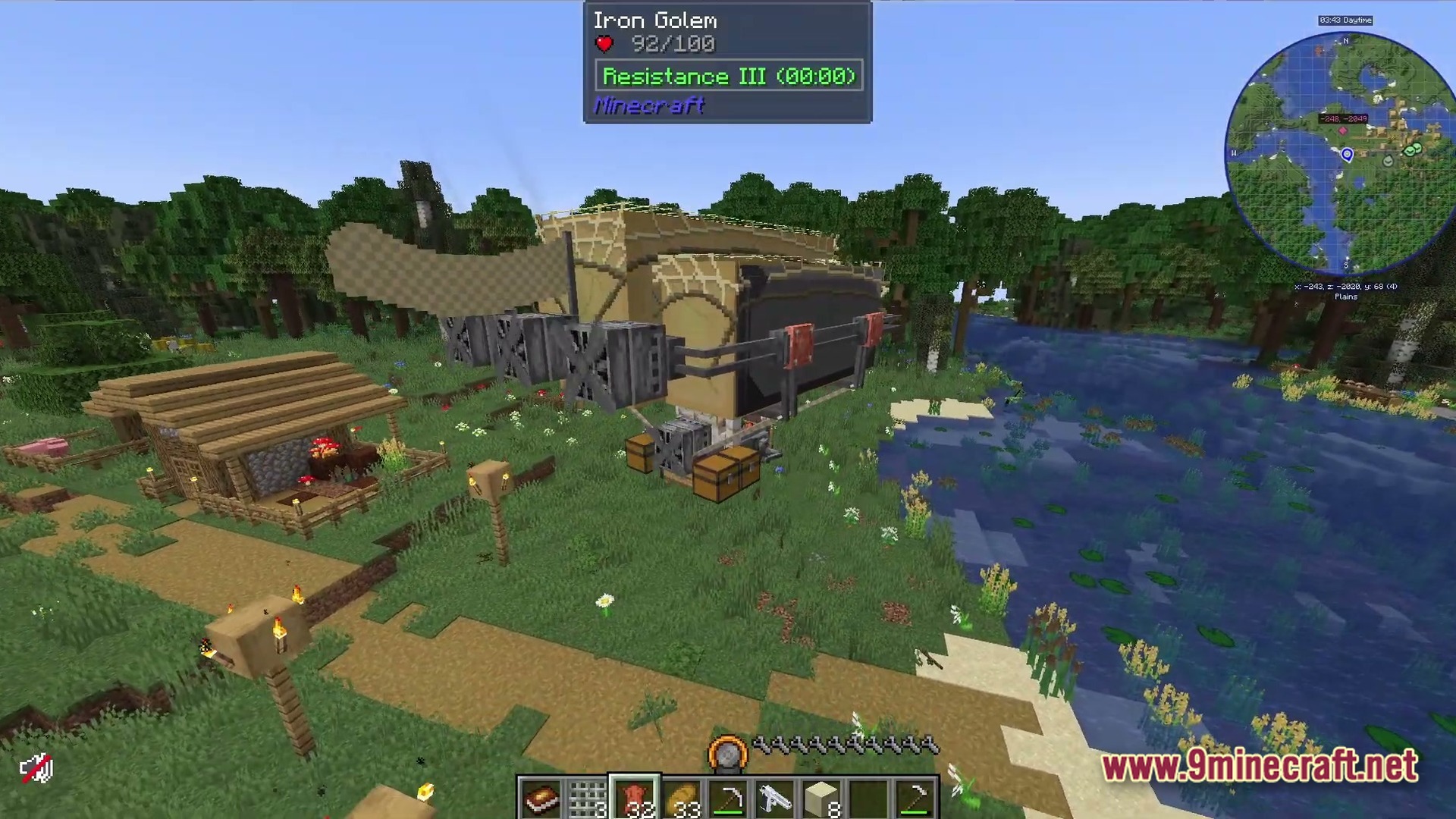 A large steampunk airship hovers over a grassy riverbank near a small wooden village structure