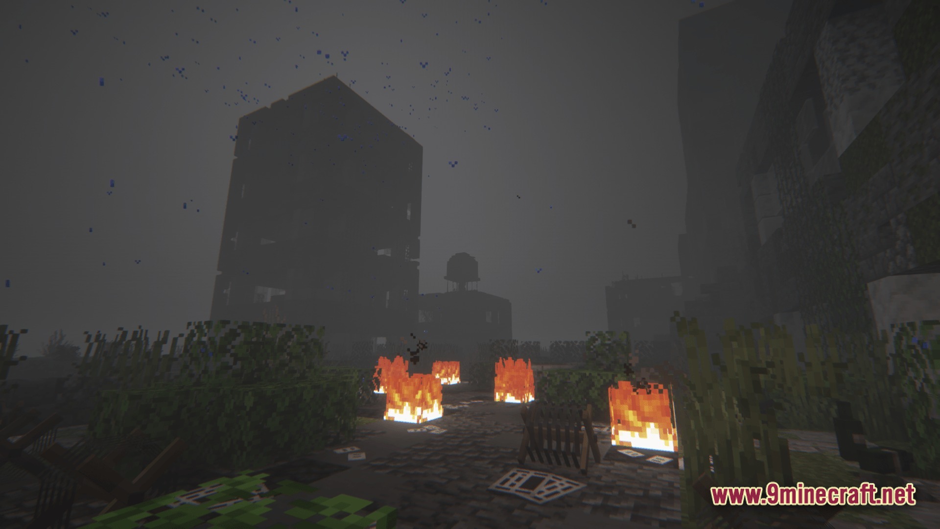 A desolate urban landscape featuring ruined buildings, scattered fires, and overgrown vegetation under a foggy sky