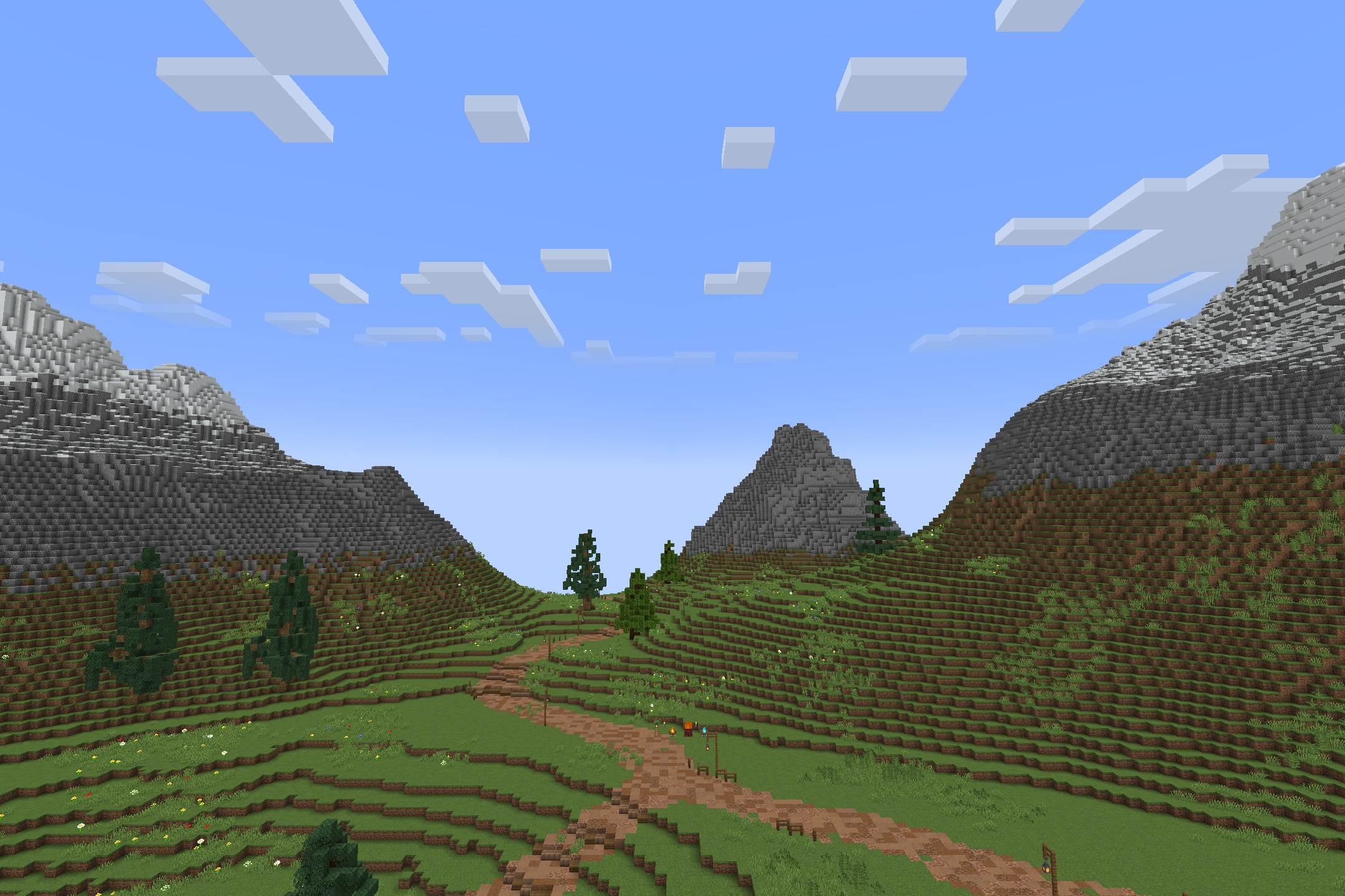 Lush green valley surrounded by tall mountains with a winding dirt path