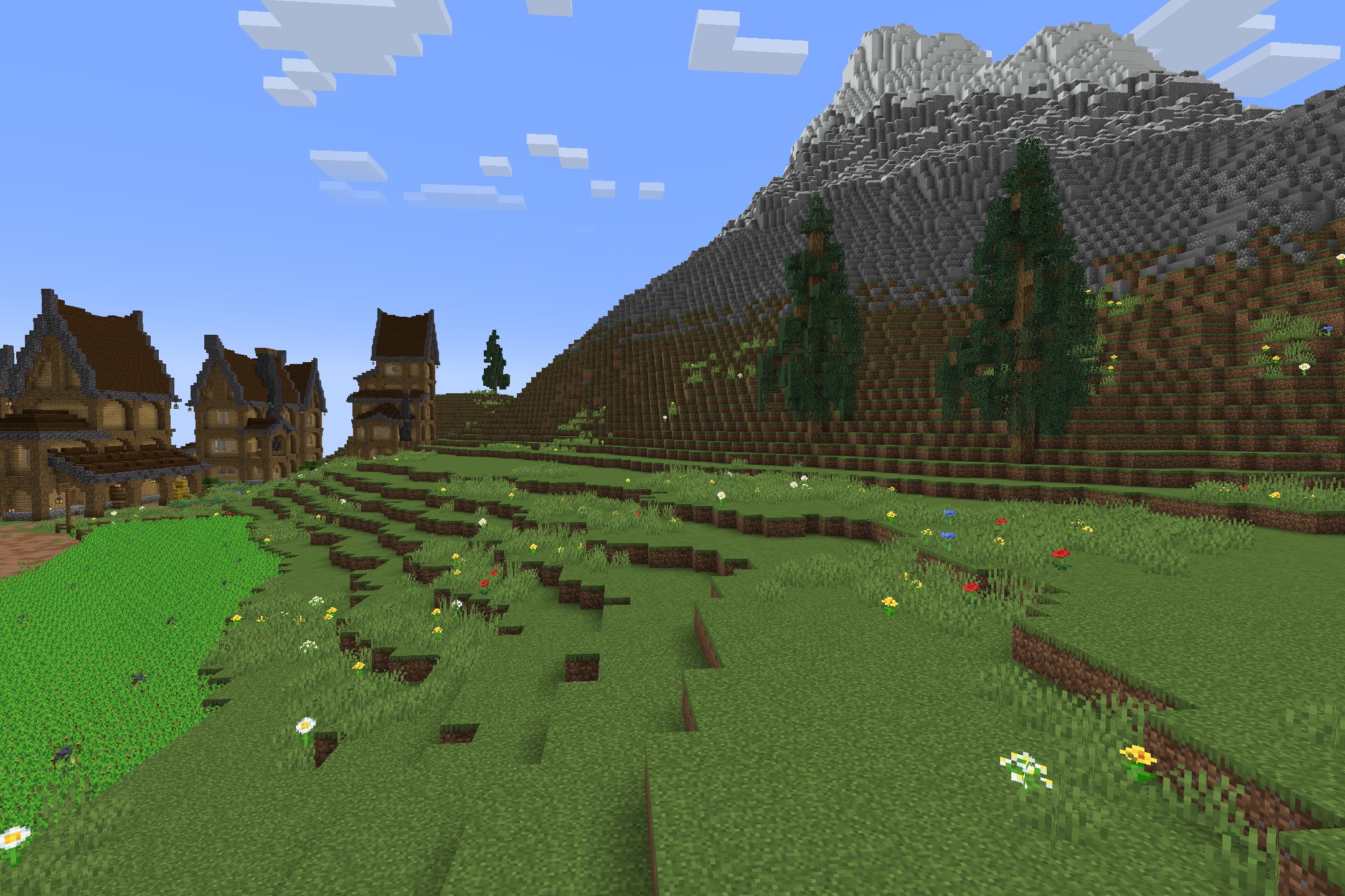 A large mountain landscape with custom houses and a field of colorful flowers