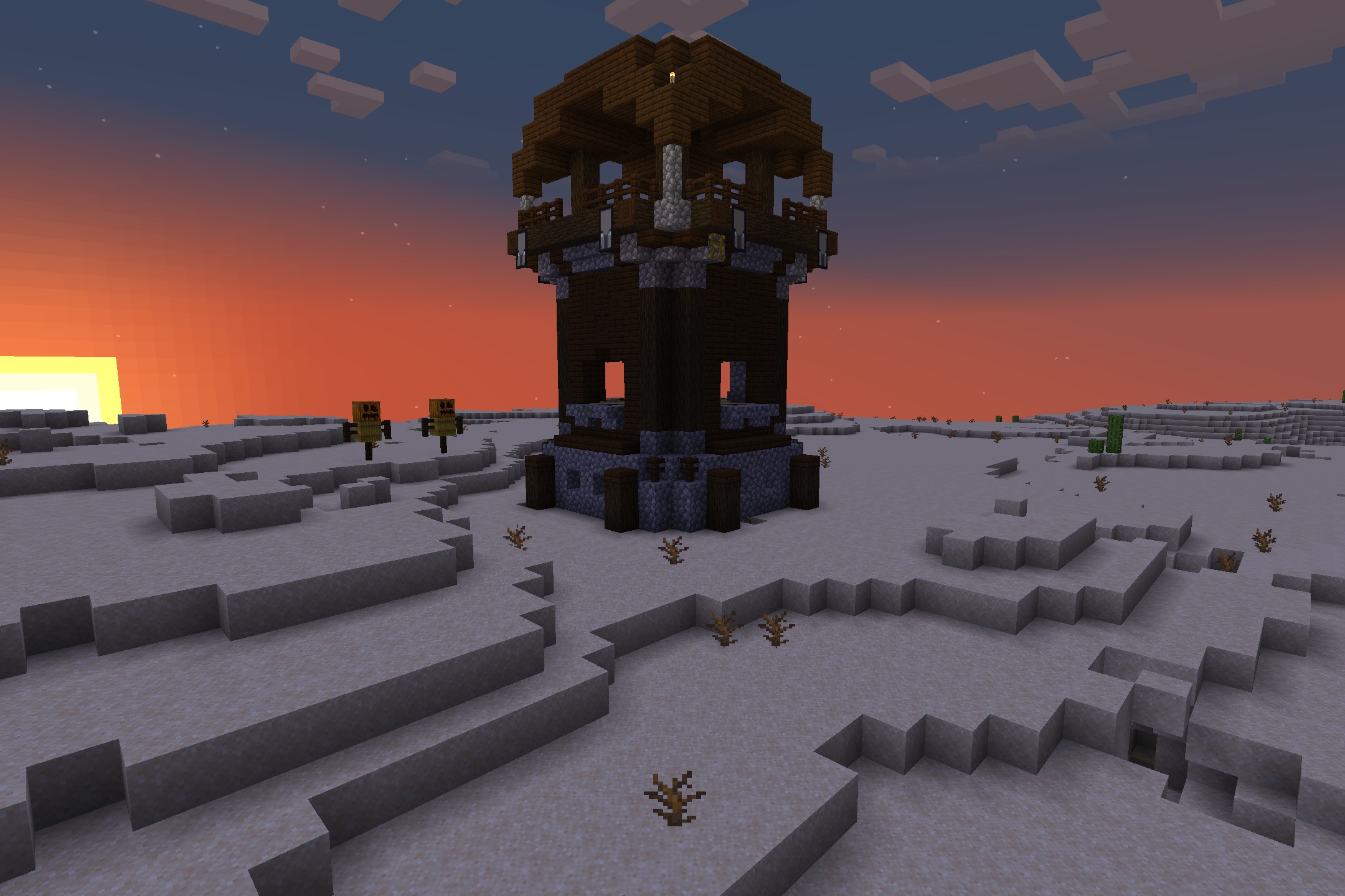 A tall pillager outpost stands in a vast desert during a sunset