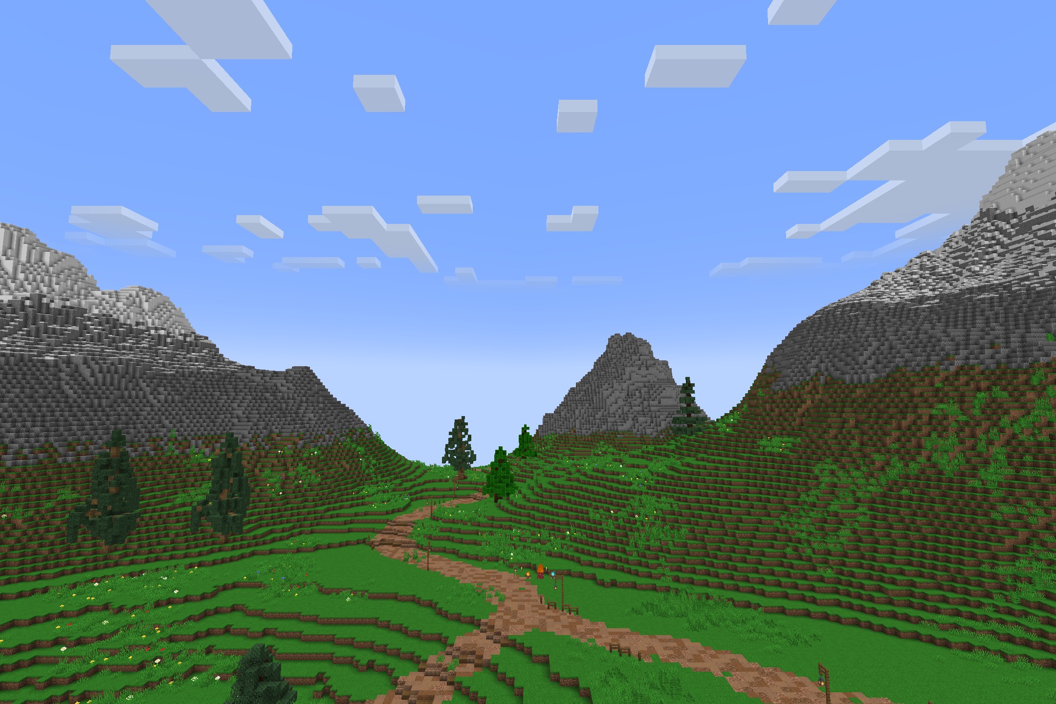 A lush green valley with a dirt path leading through mountains and trees