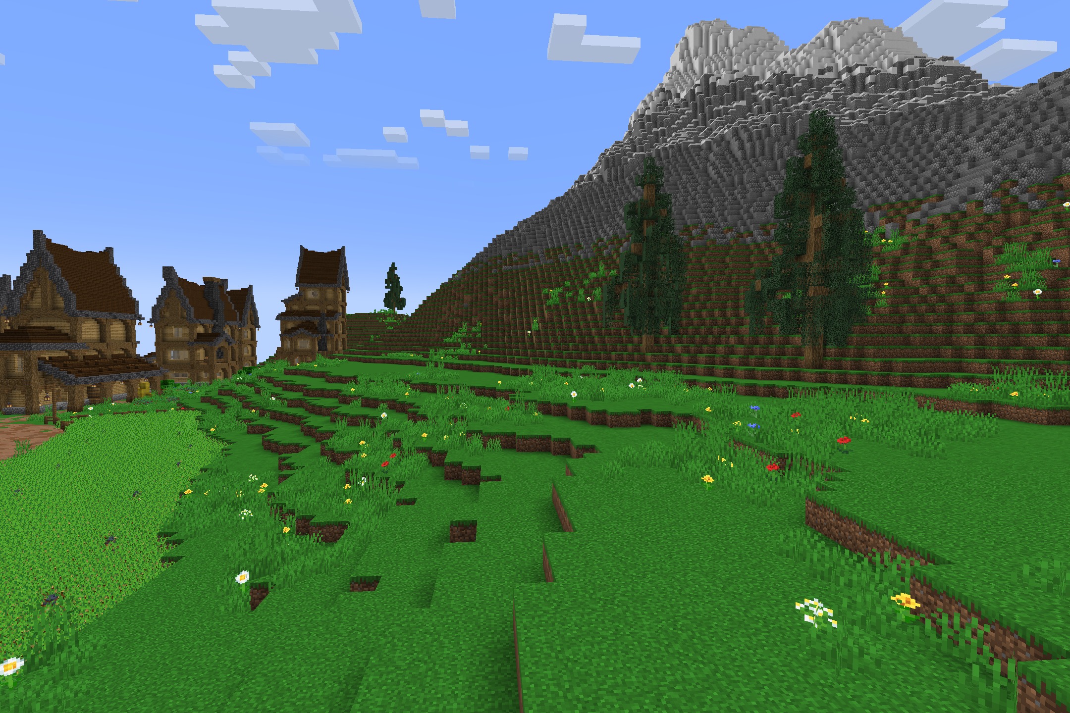 A scenic view of a large mountain next to a grassy flower field