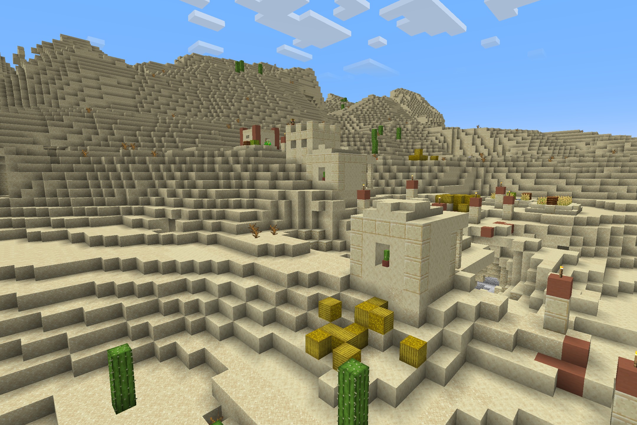 Sandstone buildings and hay bales in a desert village under a clear sky