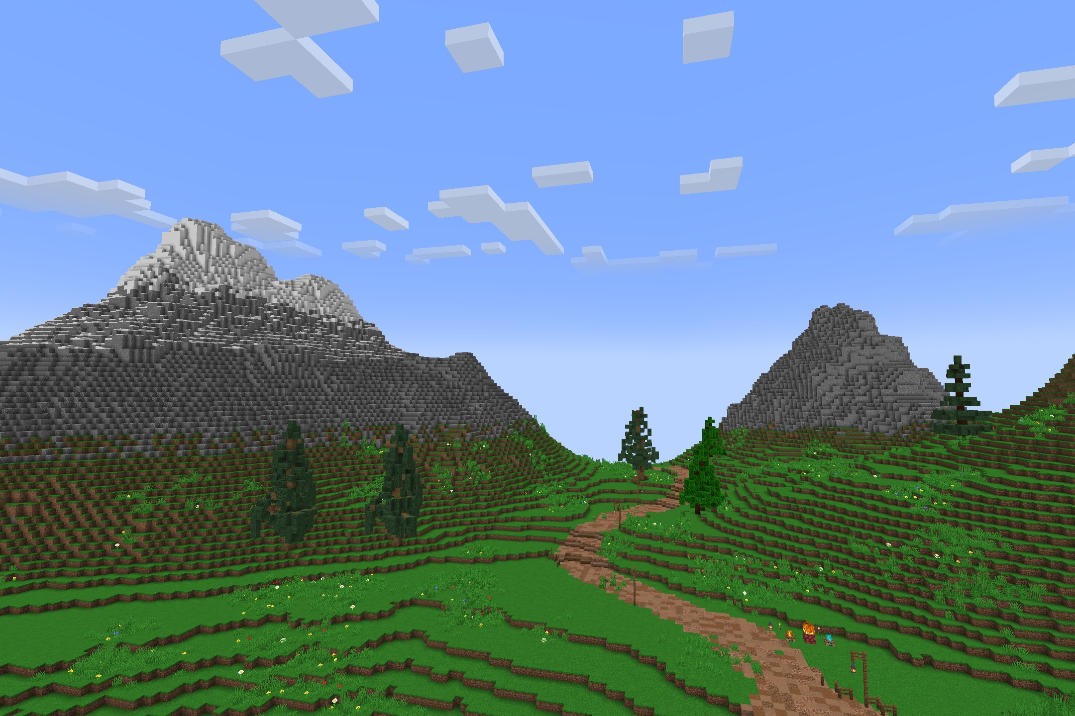 A dirt path winding through green hills toward distant snow capped mountains