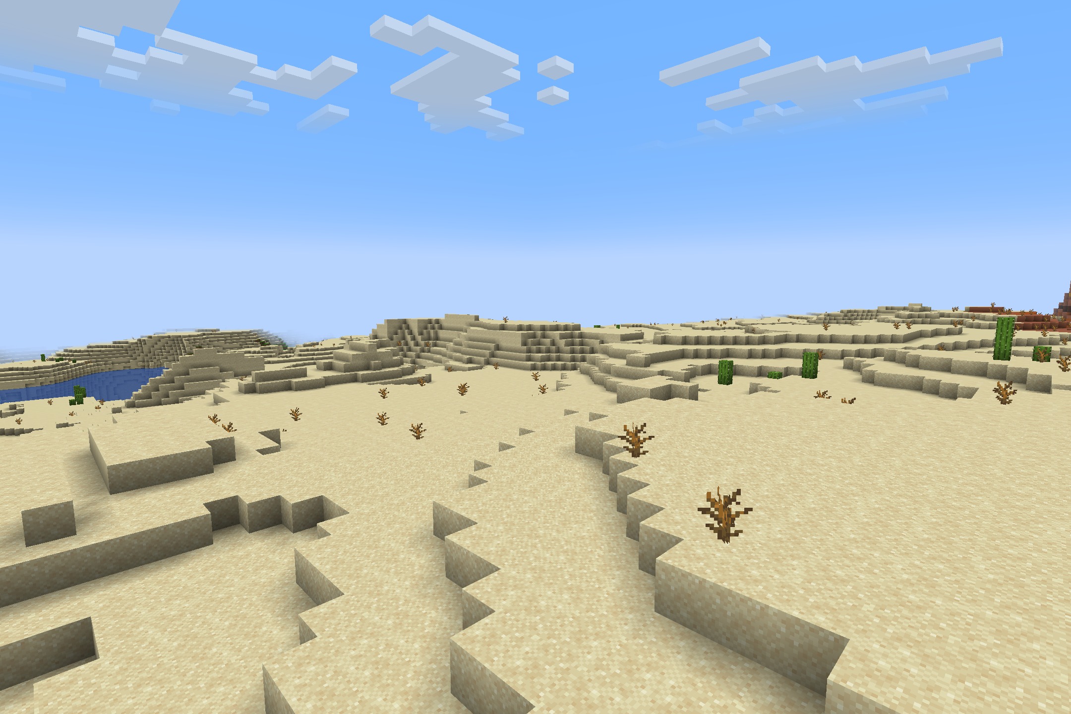 A wide desert landscape with sand dunes and dead bushes in minecraft