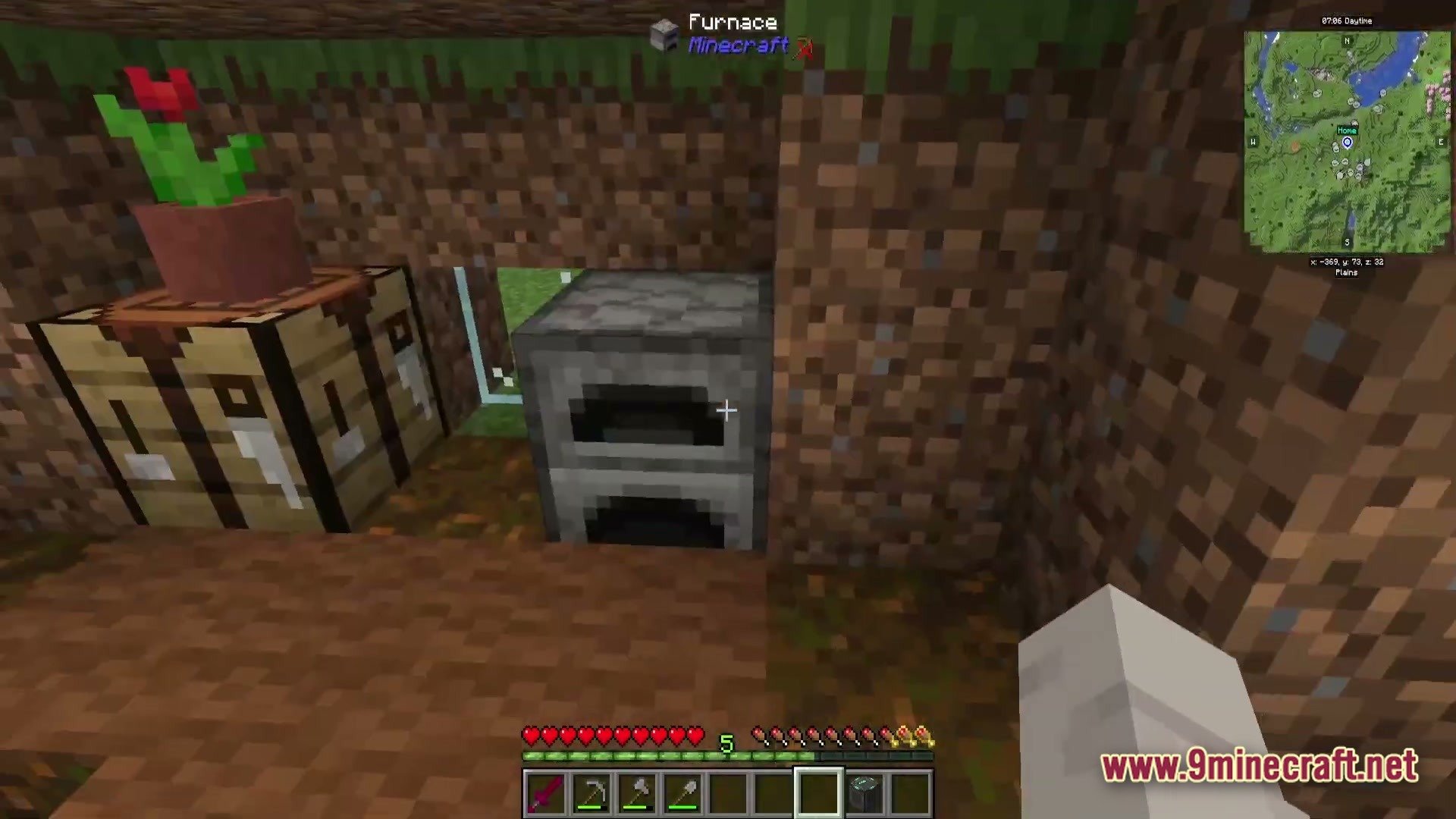 A furnace and crafting table placed inside a small dirt shelter with a minimap overlay