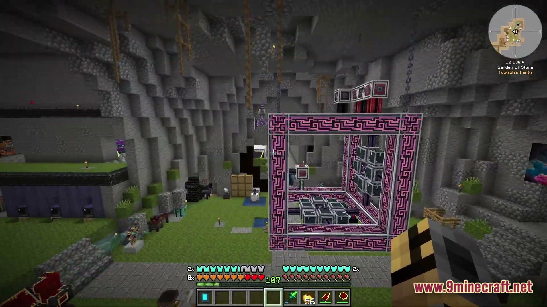 A large pink and black mechanical structure stands within a stone cavern base with various machines