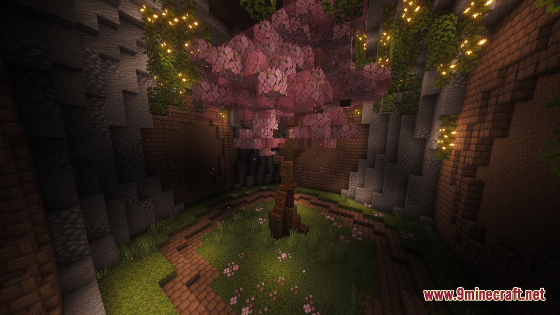 A cherry blossom tree grows in an underground stone chamber illuminated by glowing vines
