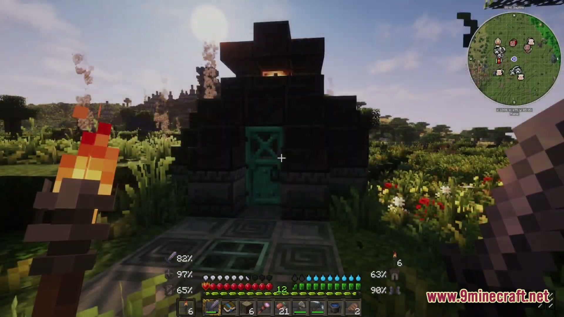 A player holds a torch before a small stone structure with a teal door in a field
