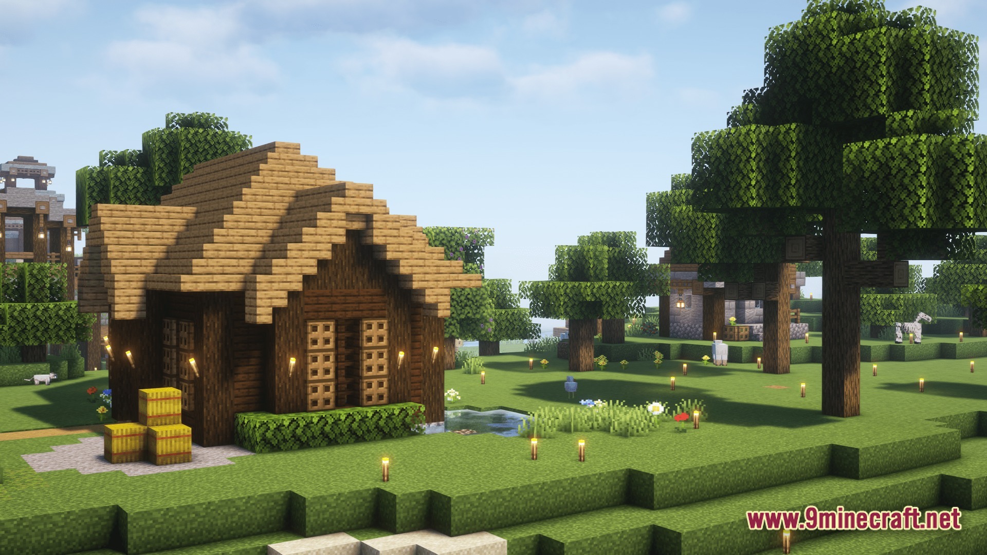 A wooden cottage with a hay bale stack sits in a grassy field under shaders