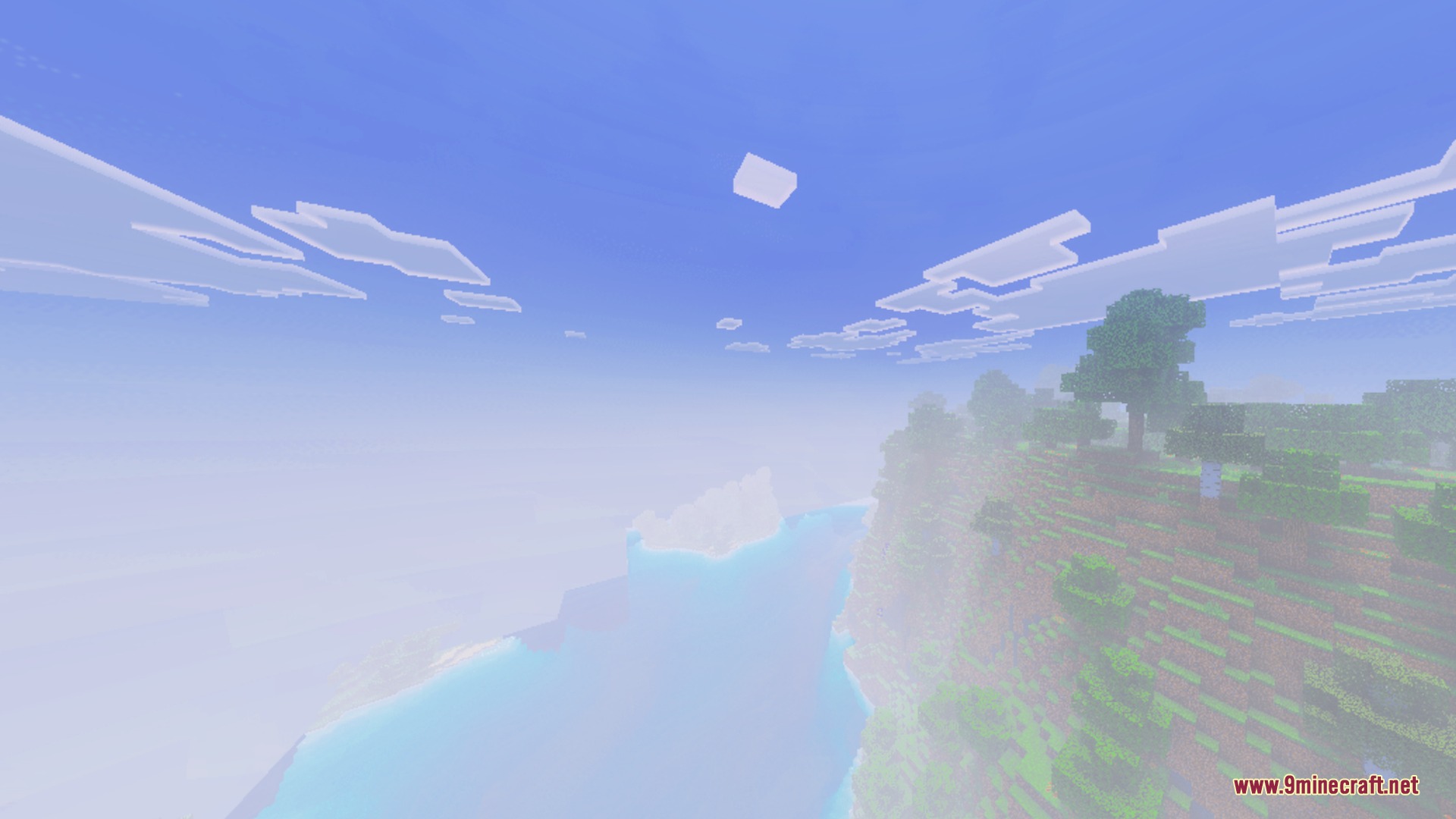 A scenic grassy cliff overlooking a bright misty ocean under soft sunlight