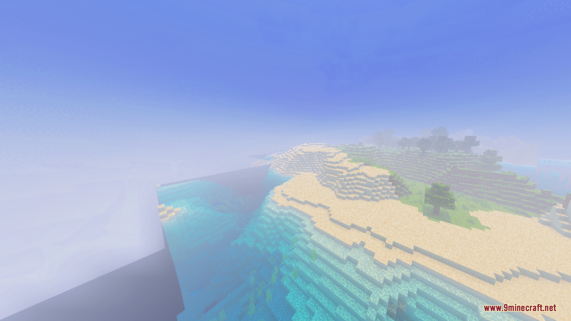 A vibrant sandy coastline with clear blue water under a bright hazy sky