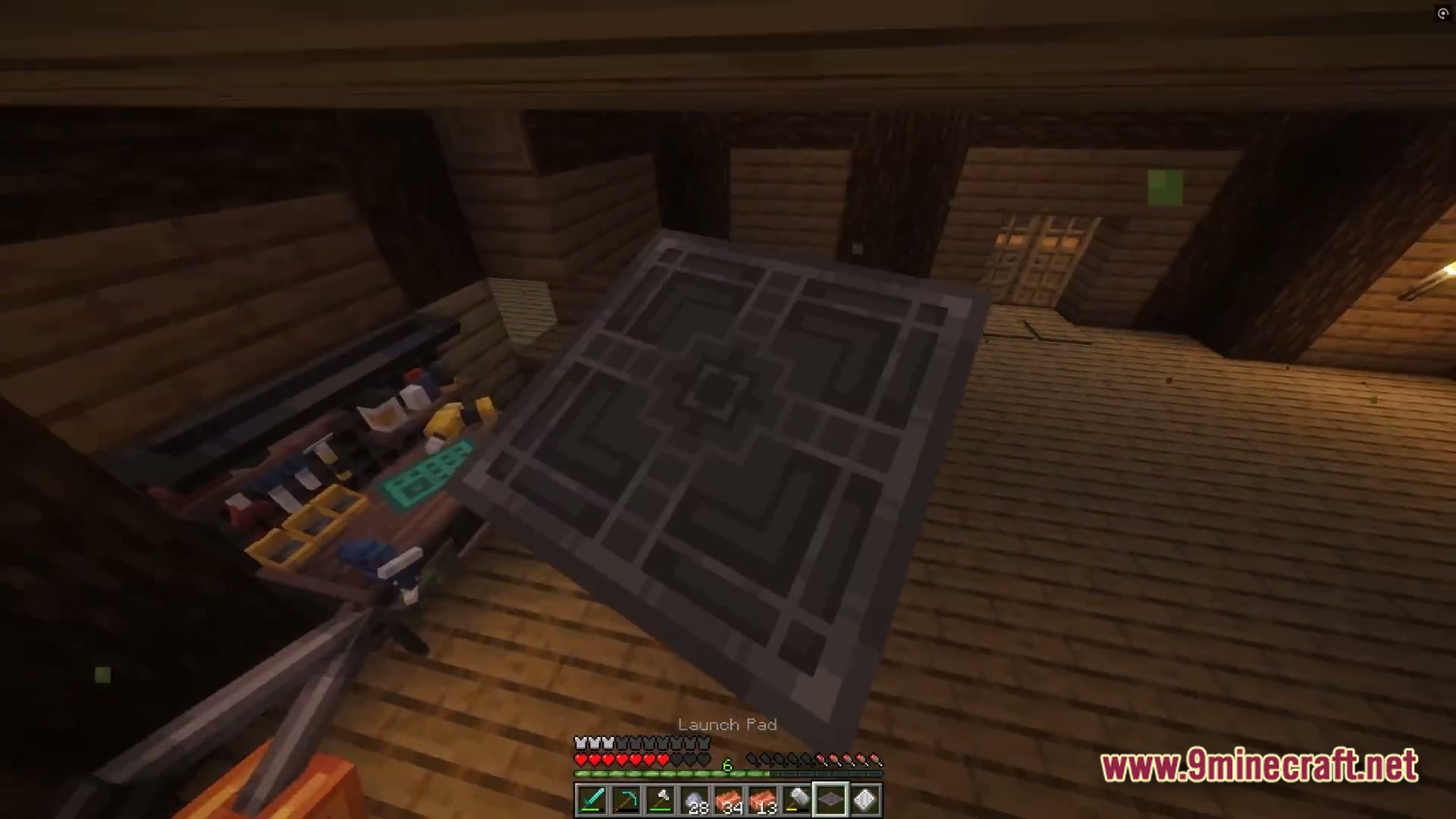 A player holds a launch pad item inside a wooden building with a workbench and tools