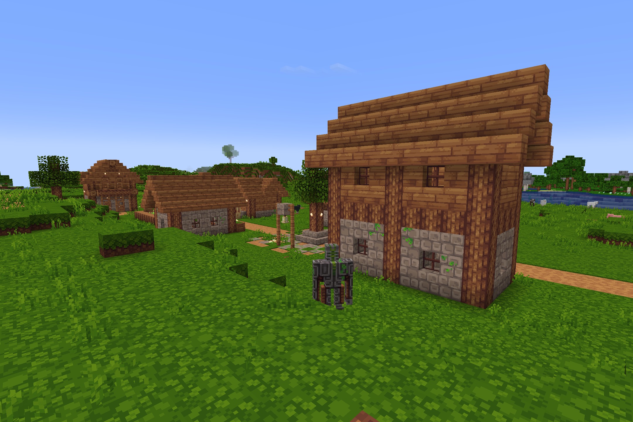 Clean wooden houses and stone buildings stand in a bright green grassy field