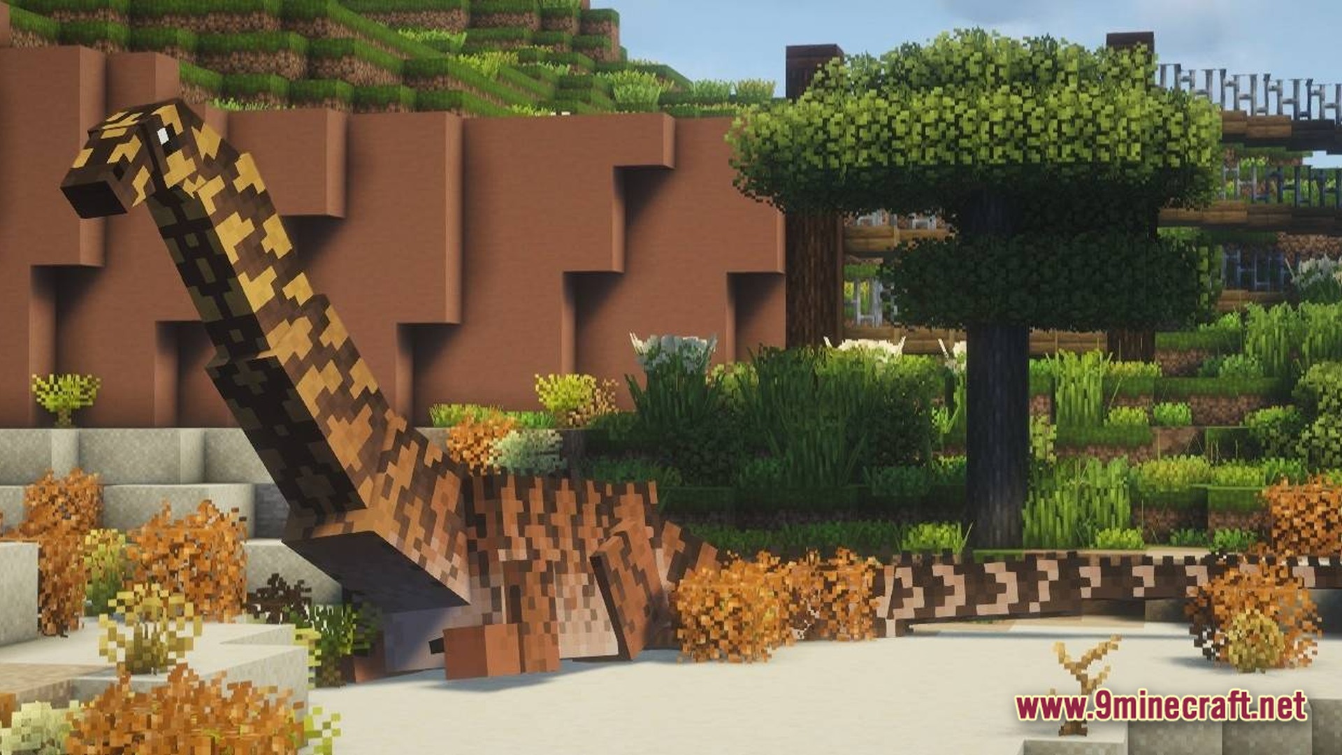 A long-necked dinosaur stands in a custom-built enclosure featuring diverse vegetation and stone walls
