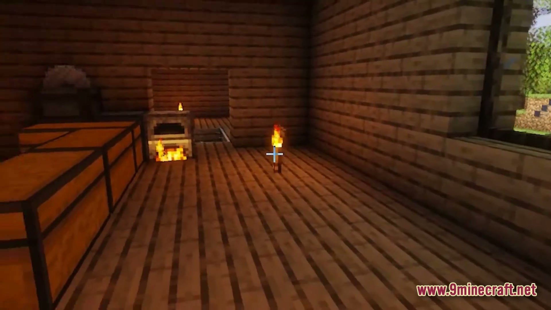 A wooden interior featuring a lit furnace, storage chests, and a torch on the floor