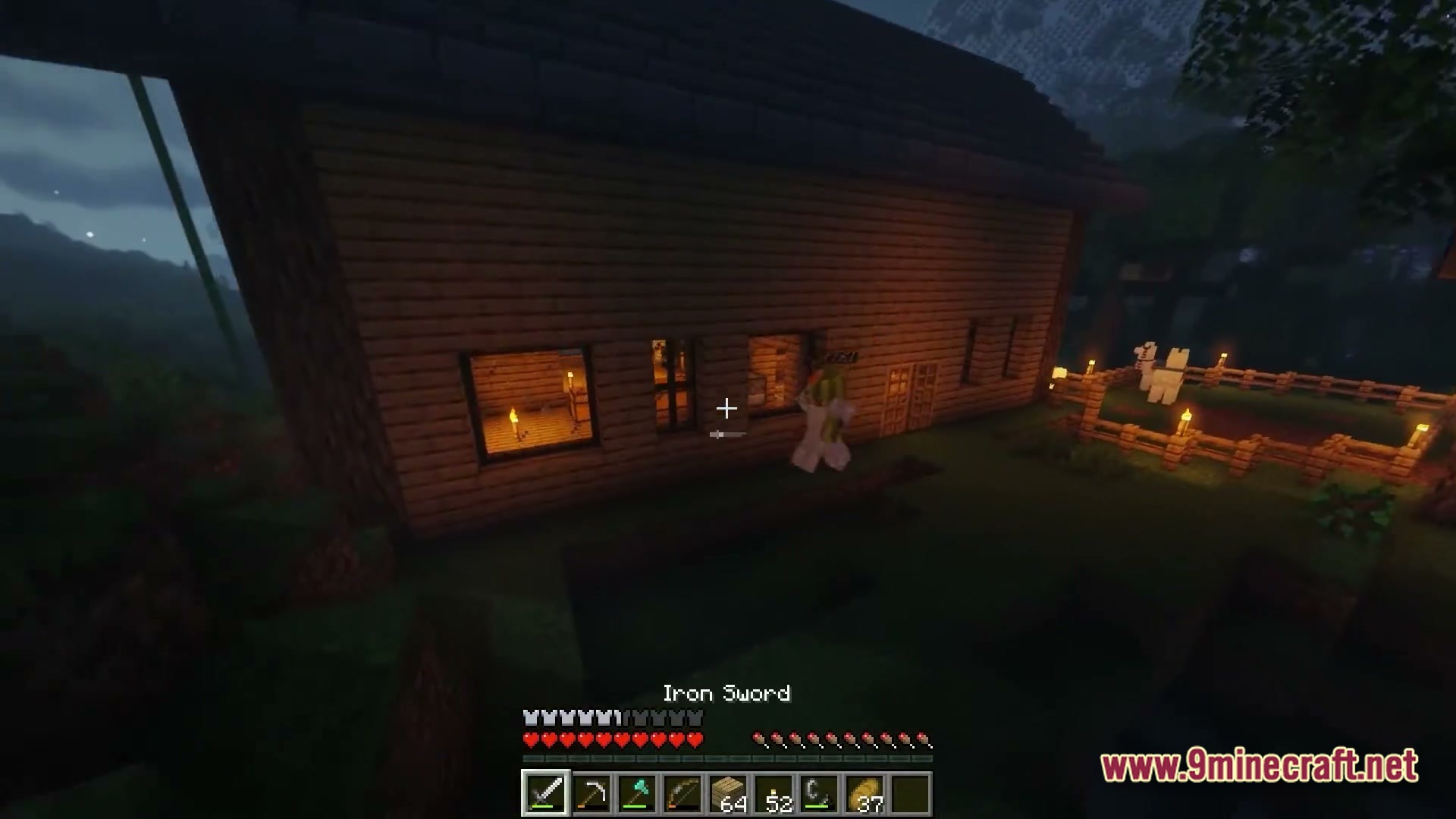 A wooden house at night with a player character standing near the windows and an animal pen
