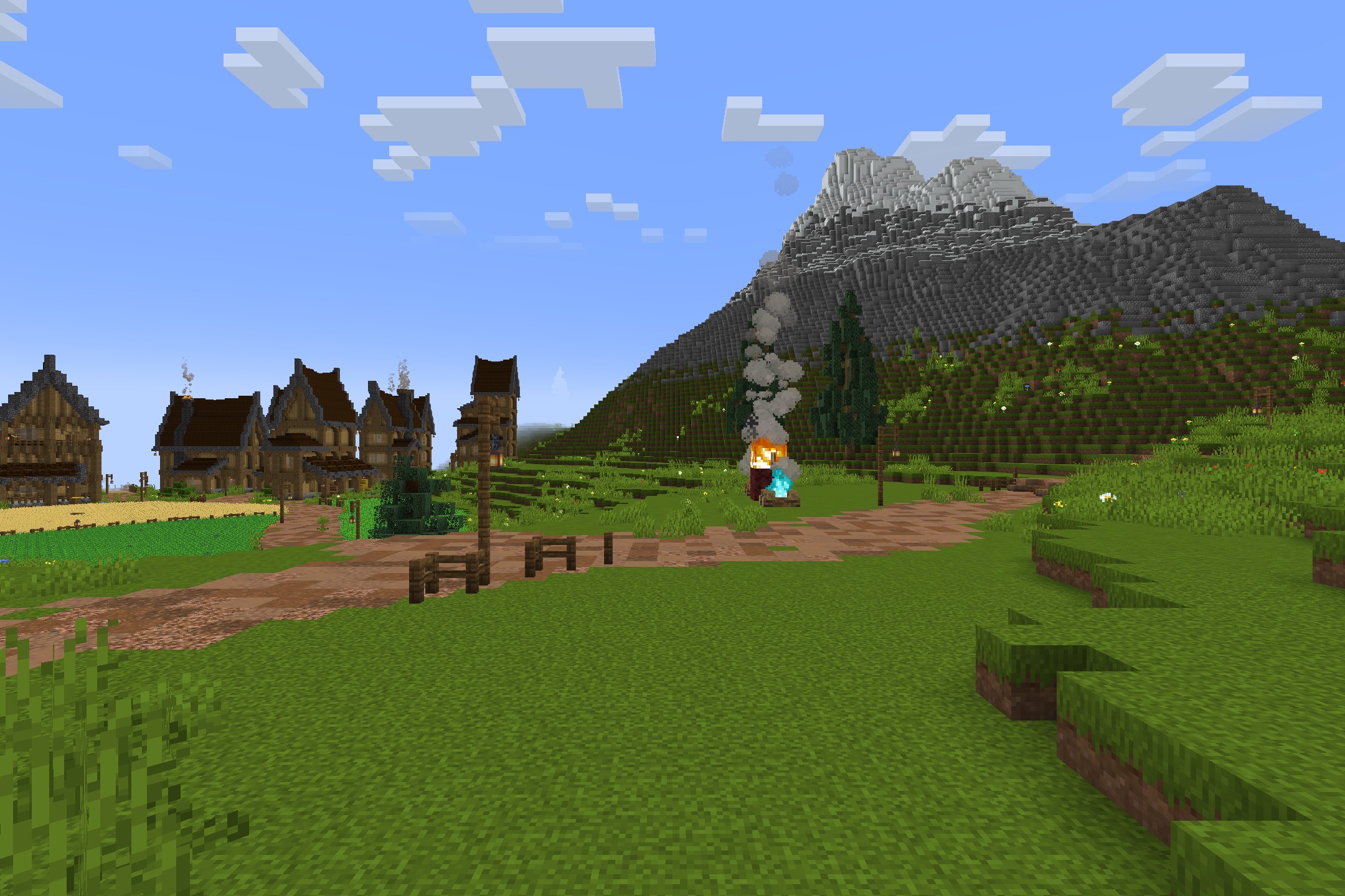 A village with wooden houses and a path leading to a large mountain