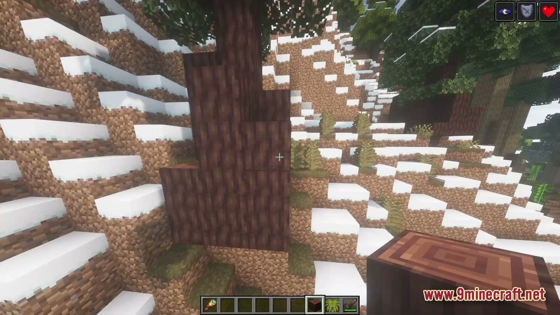 The Ancient Dawn Prehistoric Journey Modpack (1.20.1) – Survive The Age Of Giants 3 A player stands on a snowy hillside holding a dark wood log in a coniferous forest