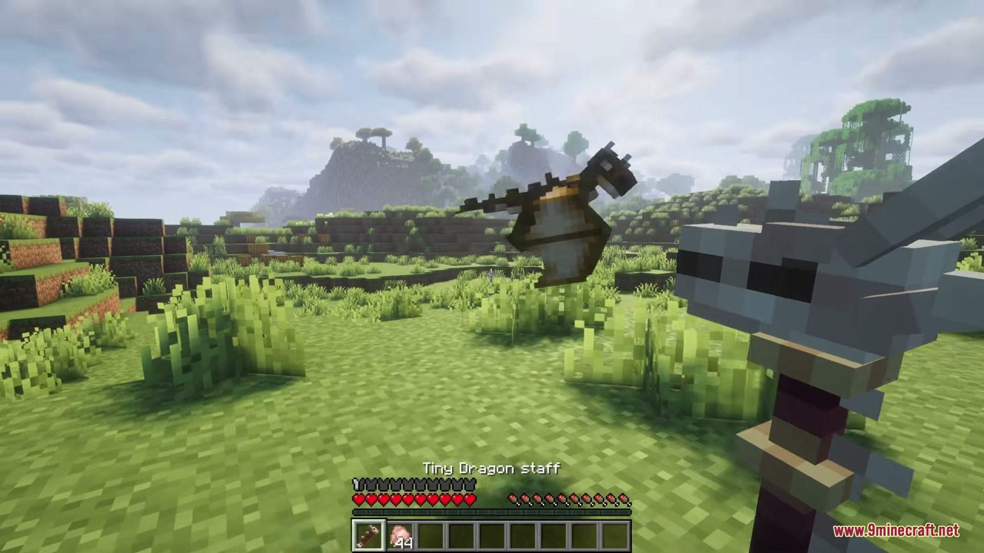 Tiny Dragons Reforged Mod (1.21.1, 1.20.1) – Hatch And Command Fire-Breathing 16 A player holding a dragon staff while a small pet dragon flies