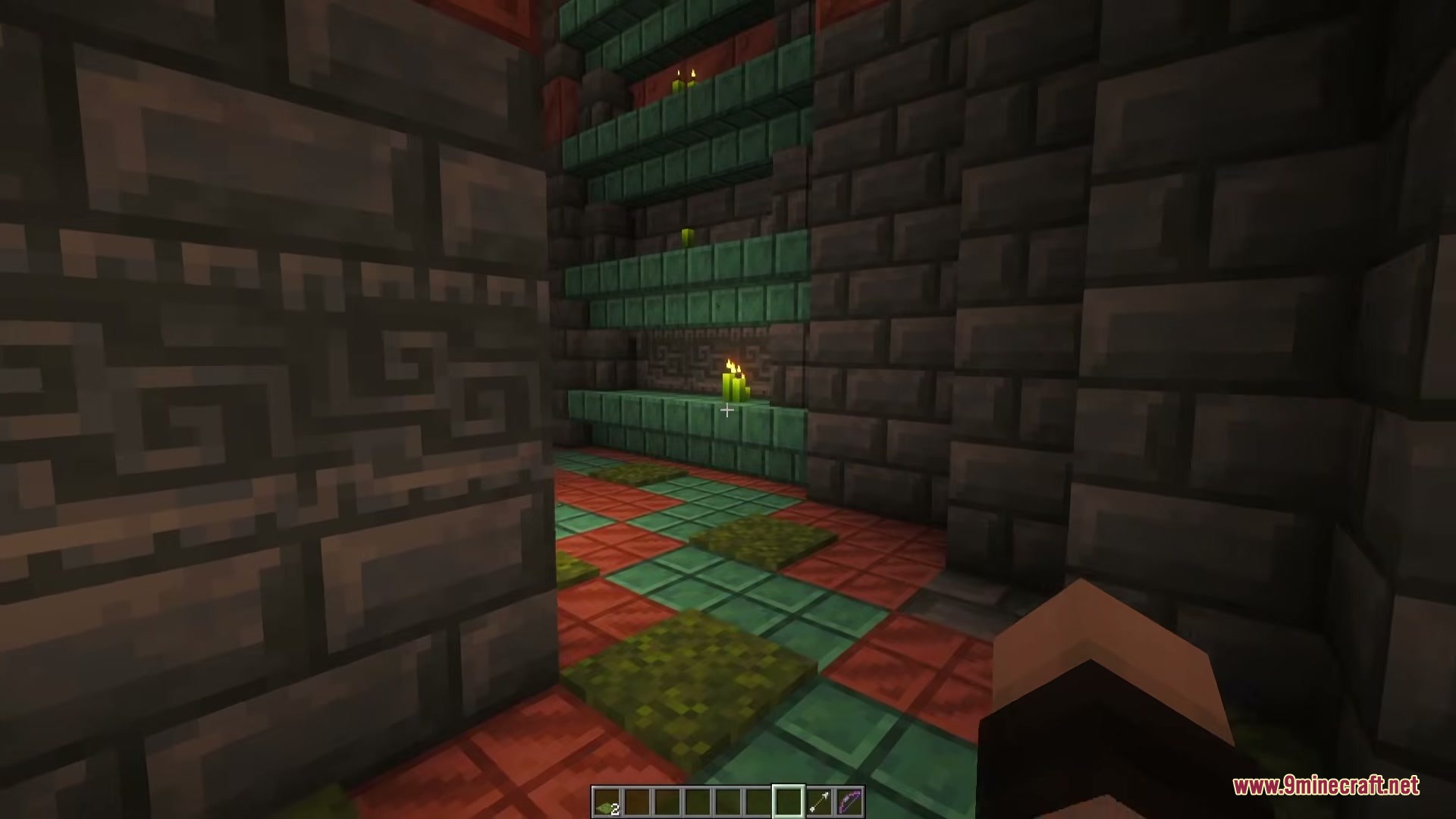 Green candles light up a room with copper shelves and tuff bricks