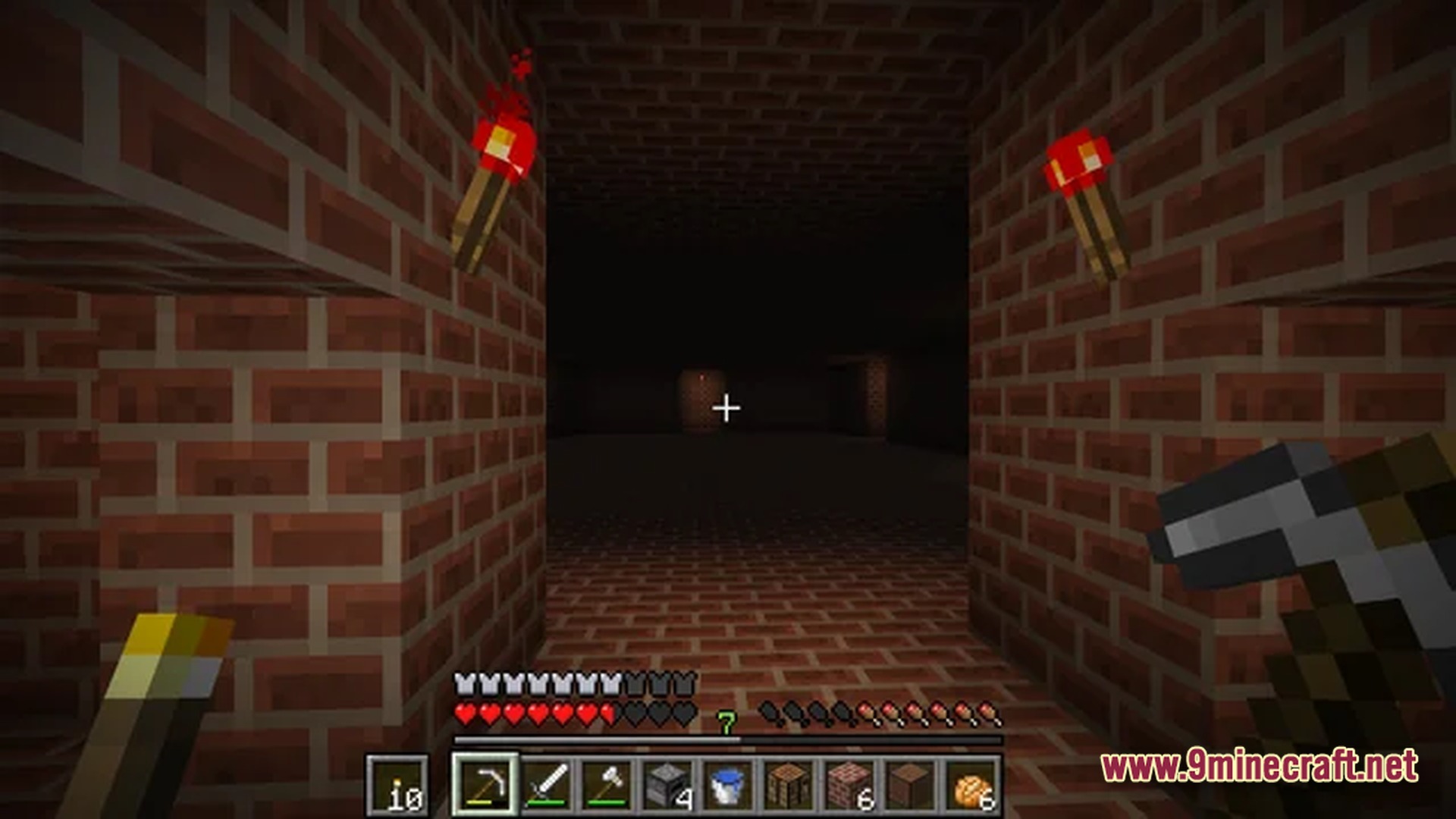 A player holding a pickaxe explores a dark brick corridor illuminated by two redstone torches