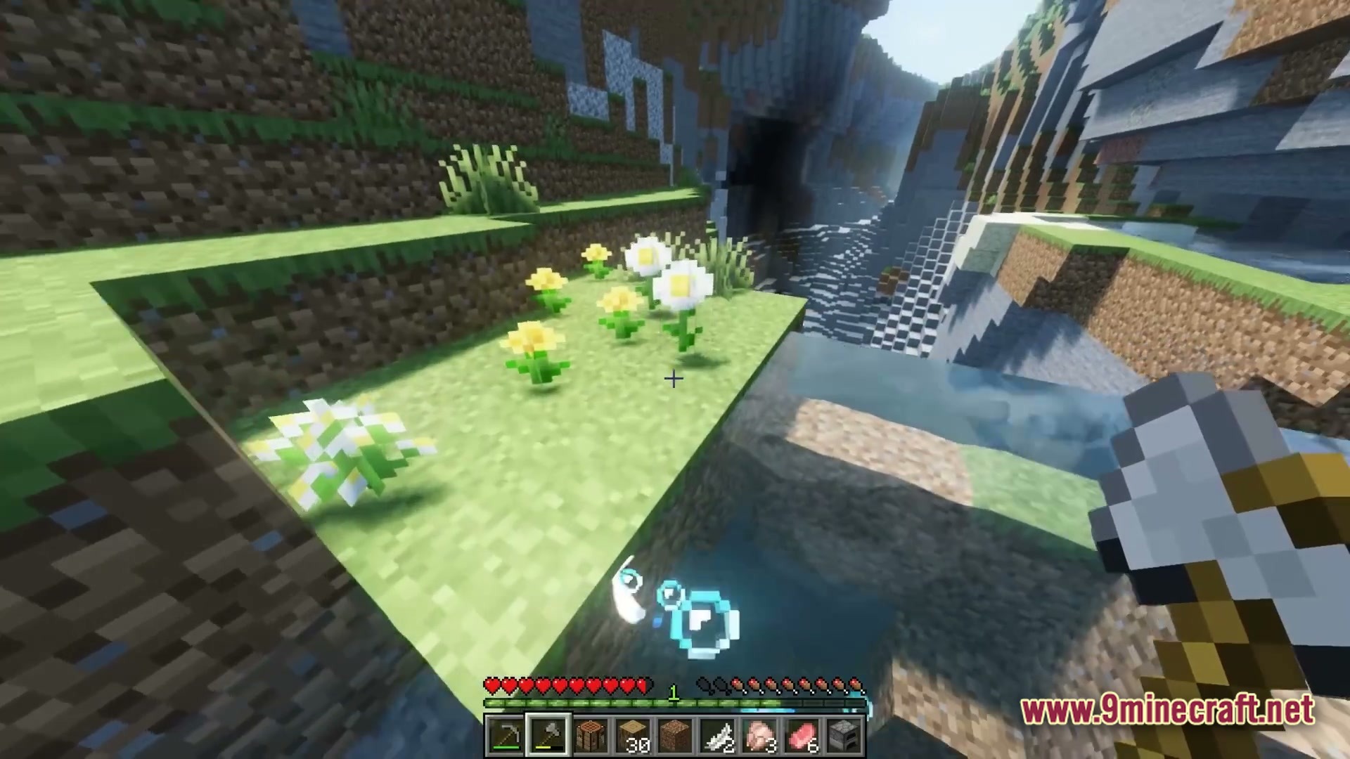 A first-person view of a player holding an axe near flowers and a mountain ravine