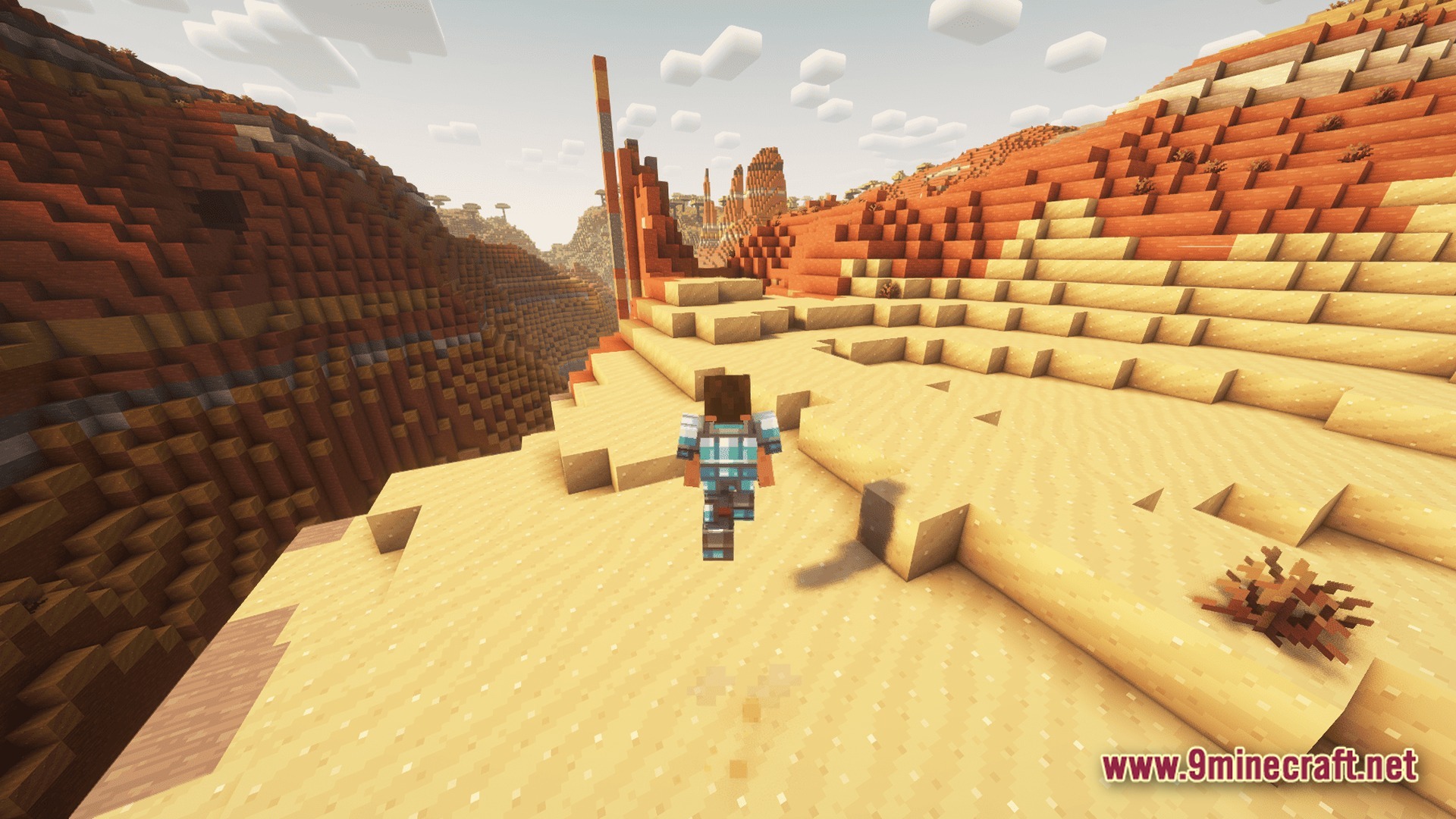 A player character wearing blue armor walks through a vast desert biome with red rock formations