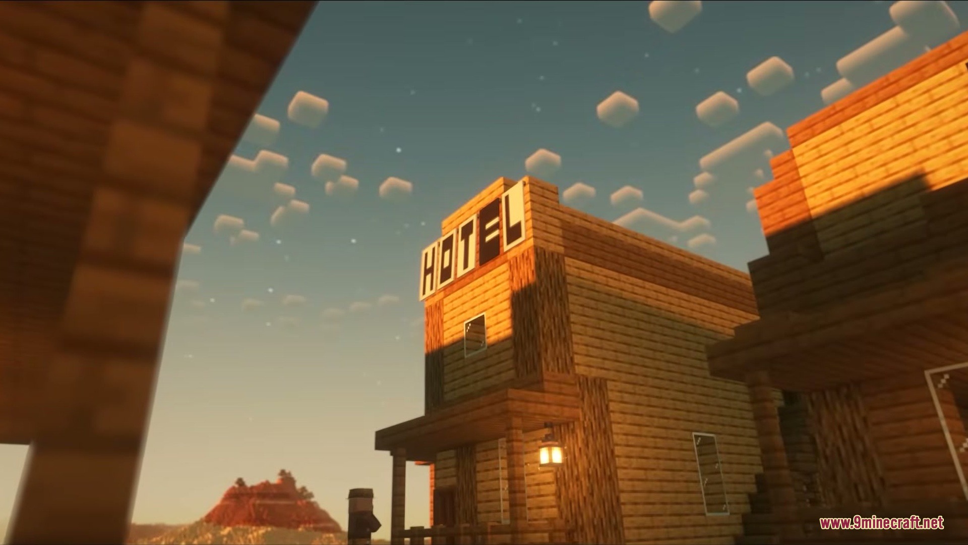 Wild West Structures Mod (1.21.8, 1.20.1) – Turn Dry Badlands Into Lively 6 A wooden frontier hotel building stands under a sunset sky in the badlands