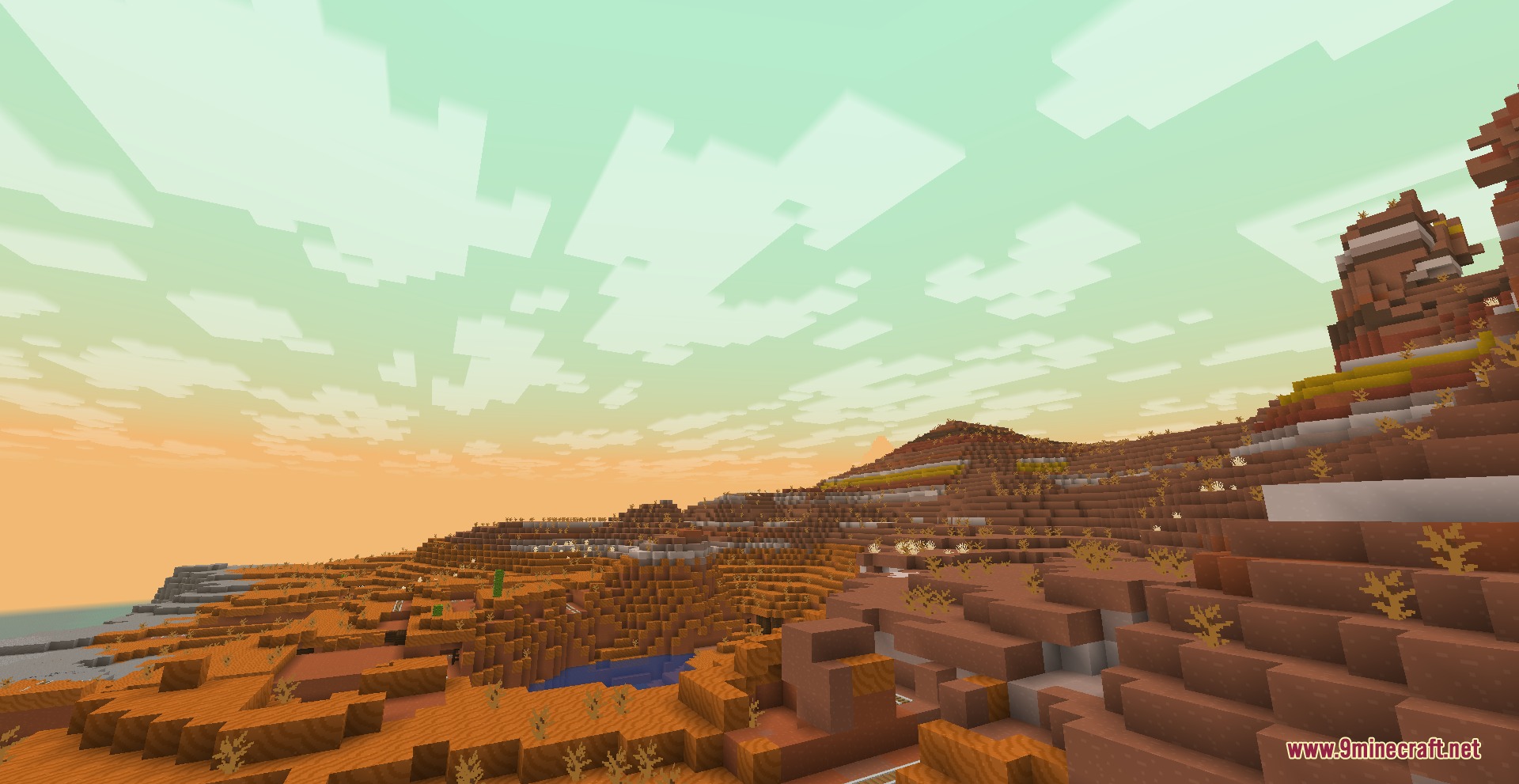 Vast badlands landscape with orange hills under a warm hazy green sky