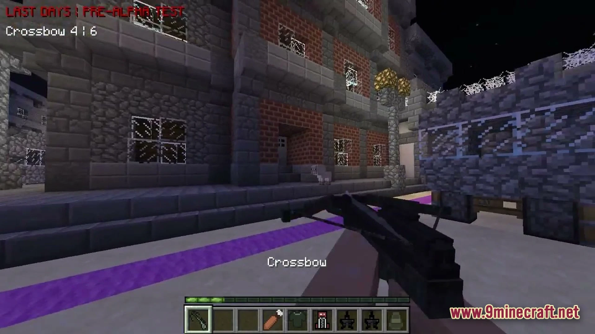 A player holds a crossbow while standing on a street outside brick and stone buildings at night