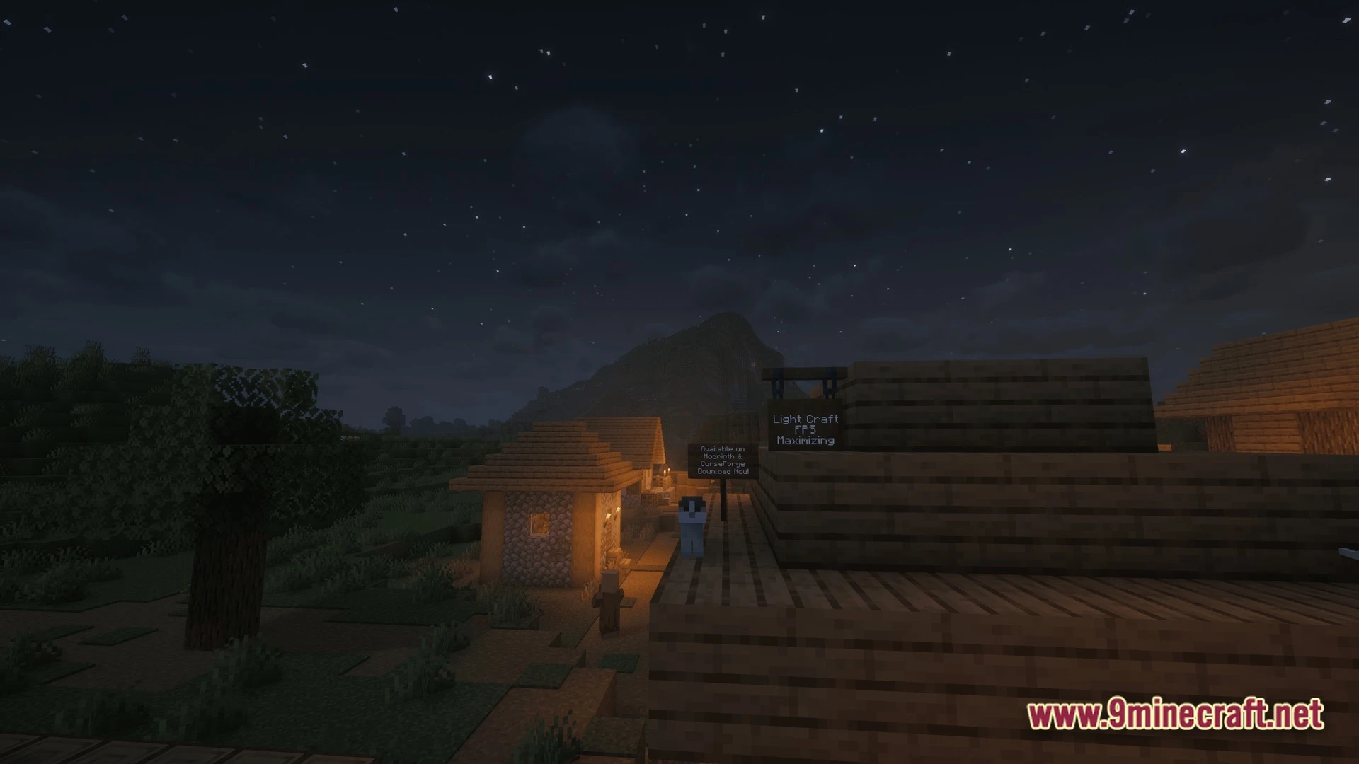 A small village at night with a mountain in the background under a starry sky